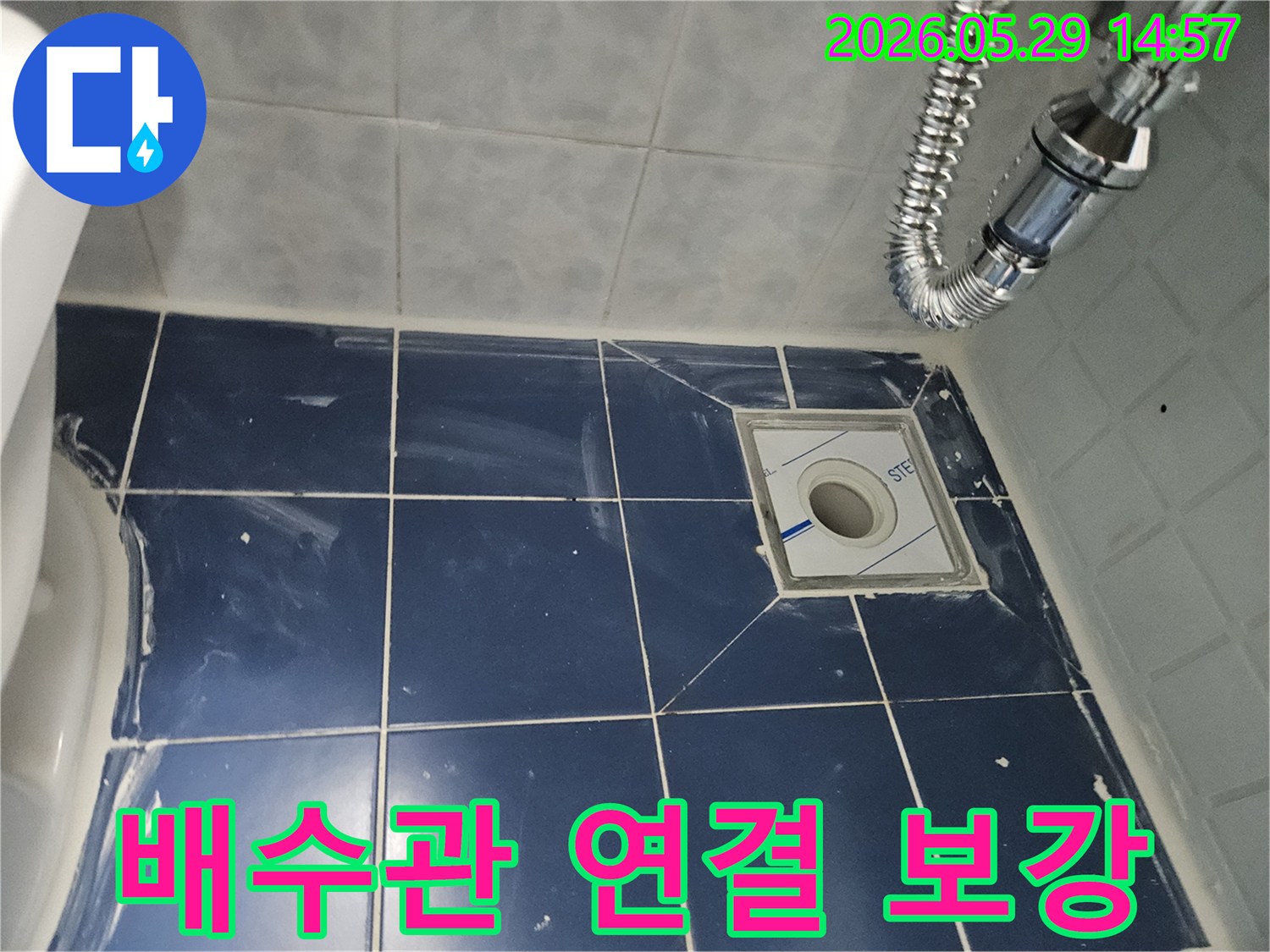 욕실 바닥의-새로운 배수구와-주변 타일-그리고 견고하게-연결된 유연한-배수관이-보이는-누수-보강-현장-사진입니다