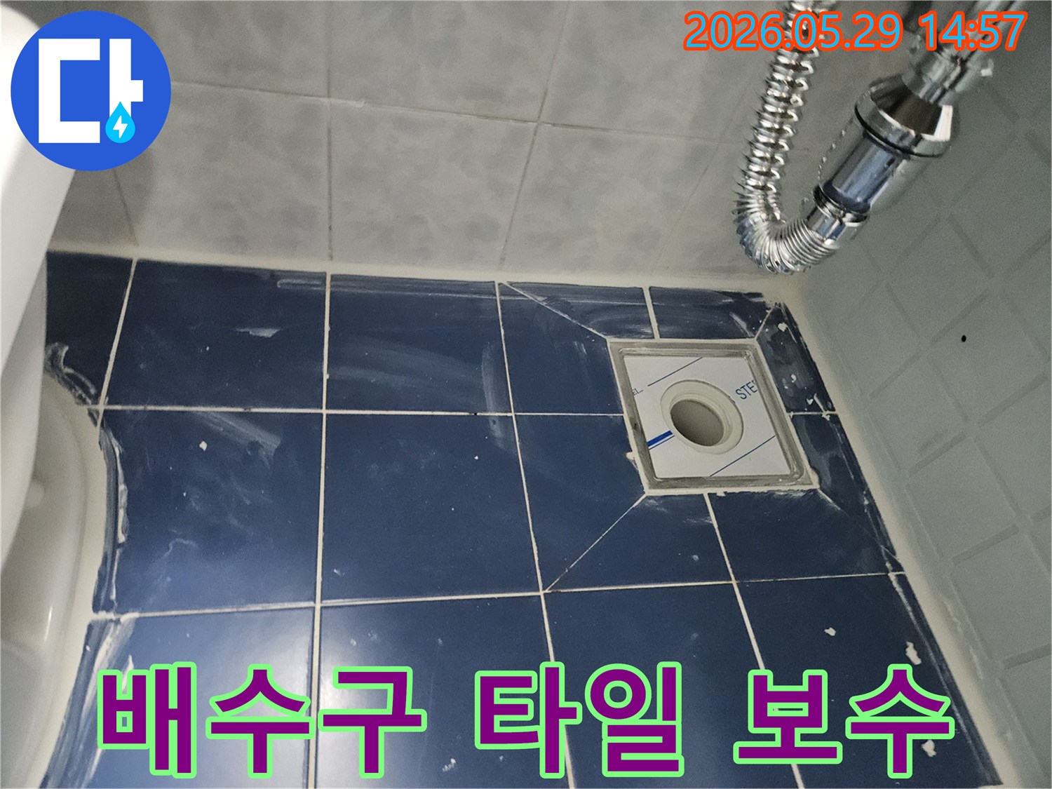 욕실 바닥의-새로운 배수구와-주변에 깔끔하게-시공된 타일-그리고 유연한 배수관이-보이는-누수-보수-완료-현장-사진입니다