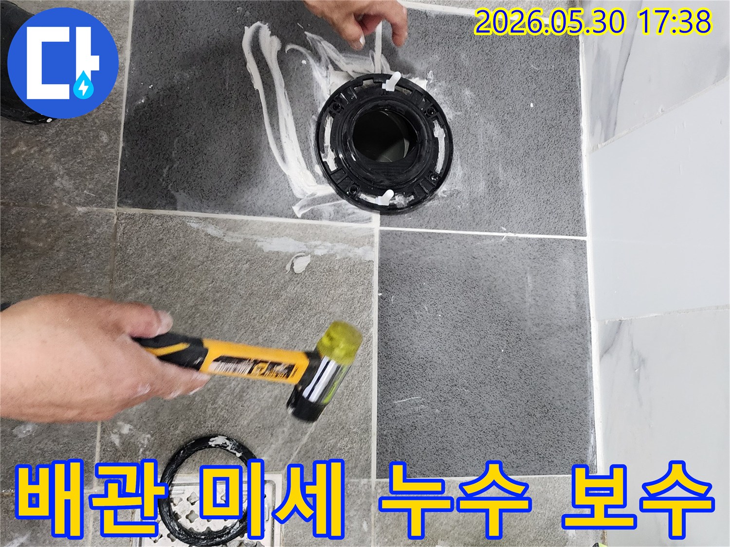욕실 바닥의 배관 연결 부위에서-발견된 미세 누수를-전문가가 정밀하게 보수하고 있으며-이는 재발 방지를 위한-핵심적인 단계입니다.