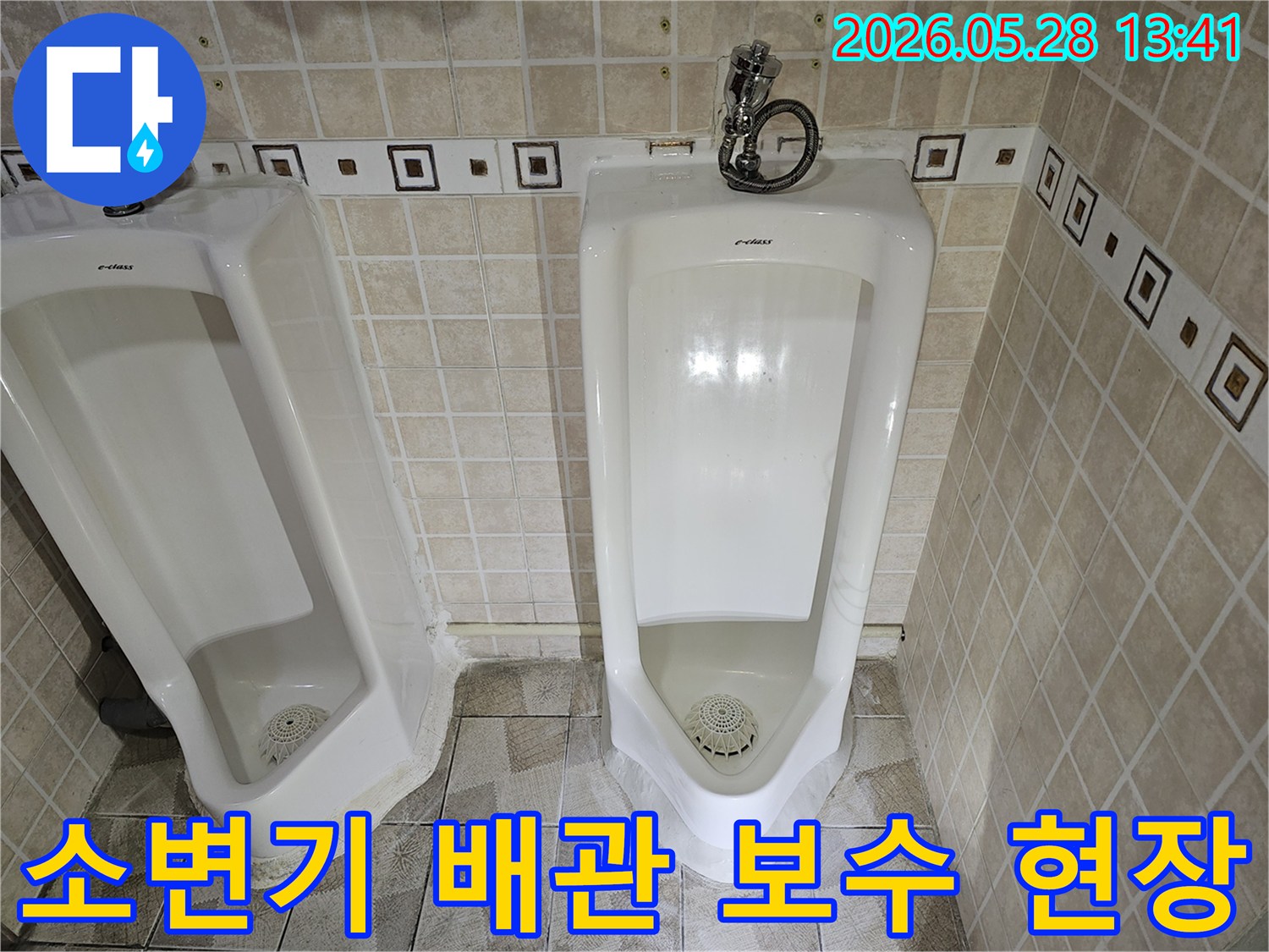 공용 화장실 소변기 배관 연결부에서-누수가 발생하여-전문가가 보수 작업을 진행하는 모습입니다.