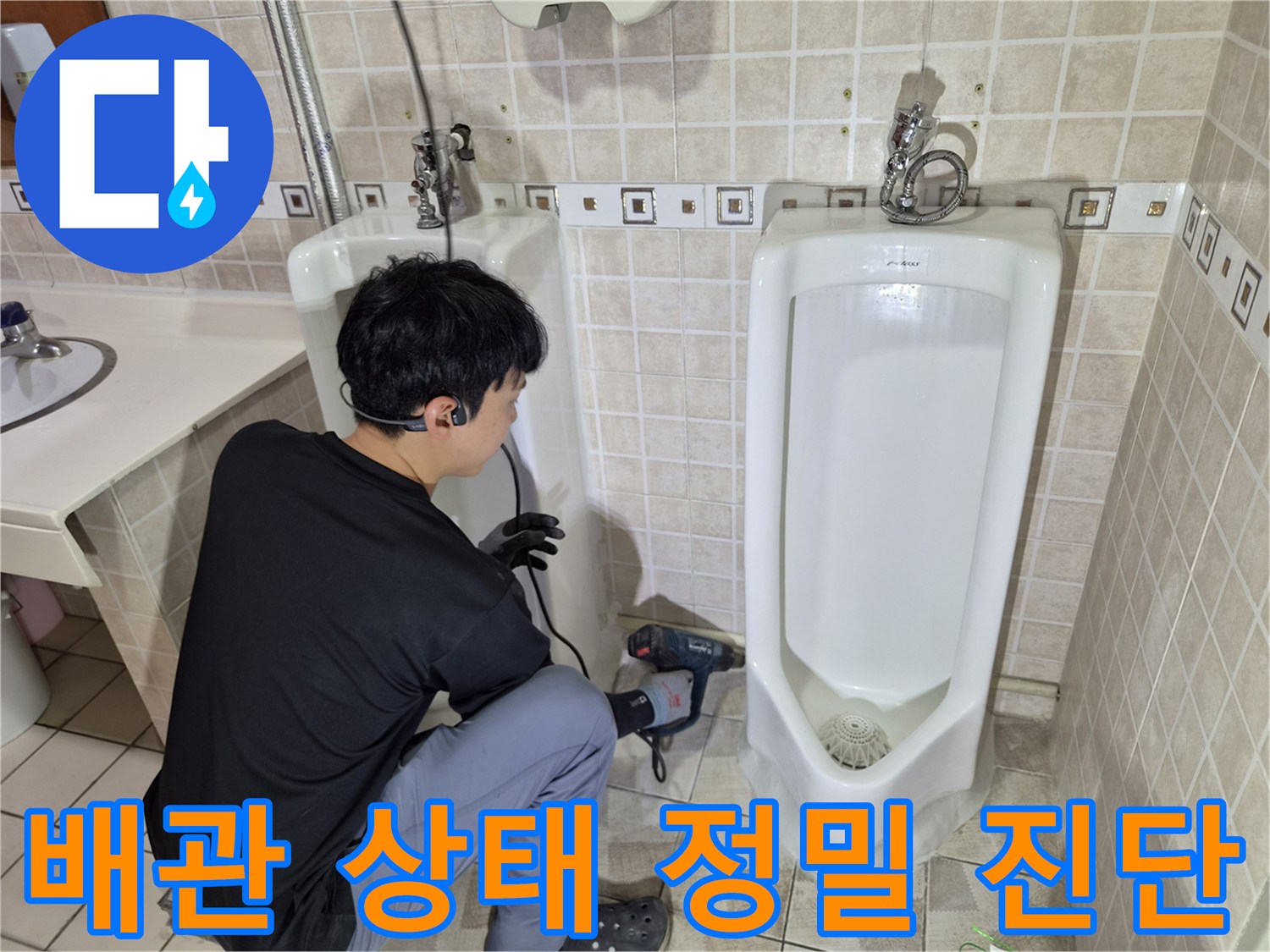 소변기 하부 배관 연결부를 점검하기 위해 장비를 사용하는 모습입니다.