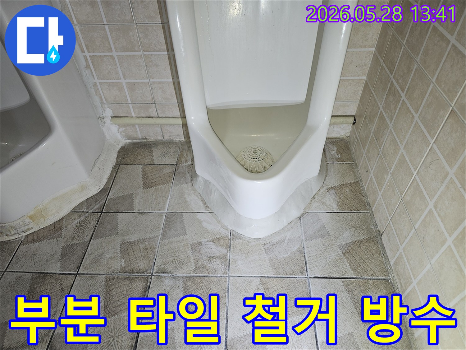 이 사진은-화장실 소변기 주변의-누수 원인을-찾기 위해-부분적으로 타일을-철거하고-방수 보수를-진행하는-상황을-보여줍니다