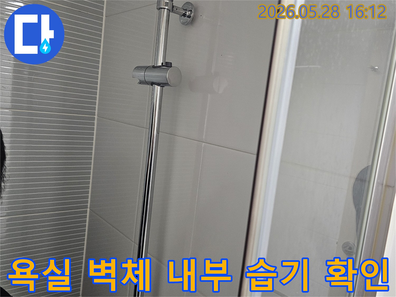 이 이미지는-욕실 샤워 공간의-벽면 타일과-설비 부위를-확대하여 촬영한 모습으로-내부 습기 여부를-판단하는 데-도움이 됩니다.