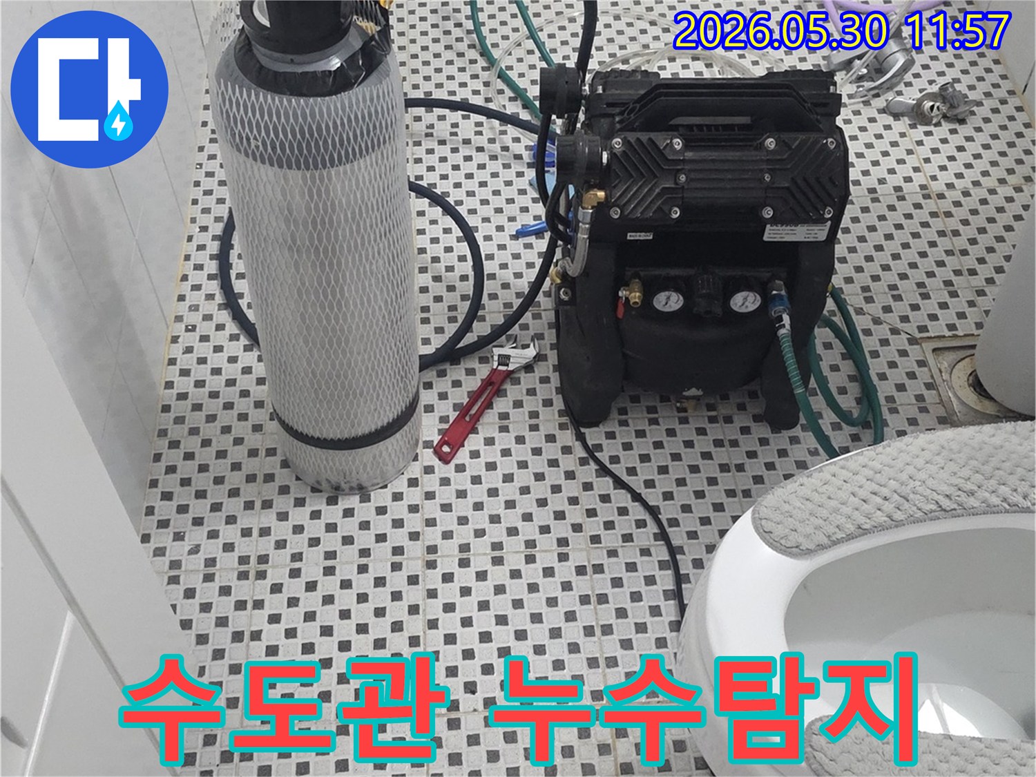 이 이미지는 상계동에서-수도관 누수-탐지를 위해-고압 공기 주입 장비와-가스 실린더를 사용하고 있는-전문적인 작업 현장을 보여줍니다.