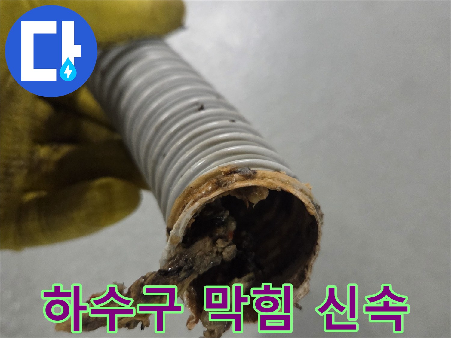 노란 장갑을 낀 손이-신속한 처리가 필요한-이물질로 막힌 배수관을 들고 있습니다.