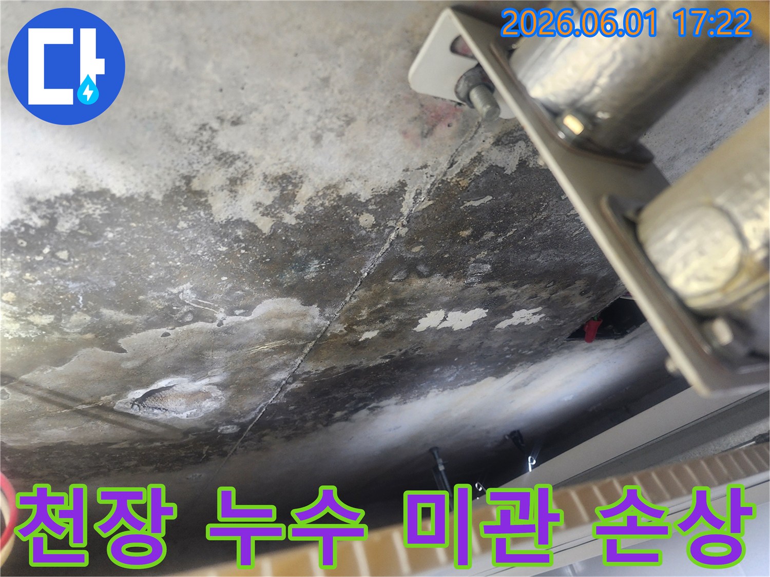누수로 인해 얼룩지고 변색된 콘크리트 천장 표면-배관 지지대 주변의 물기 흔적과 오염