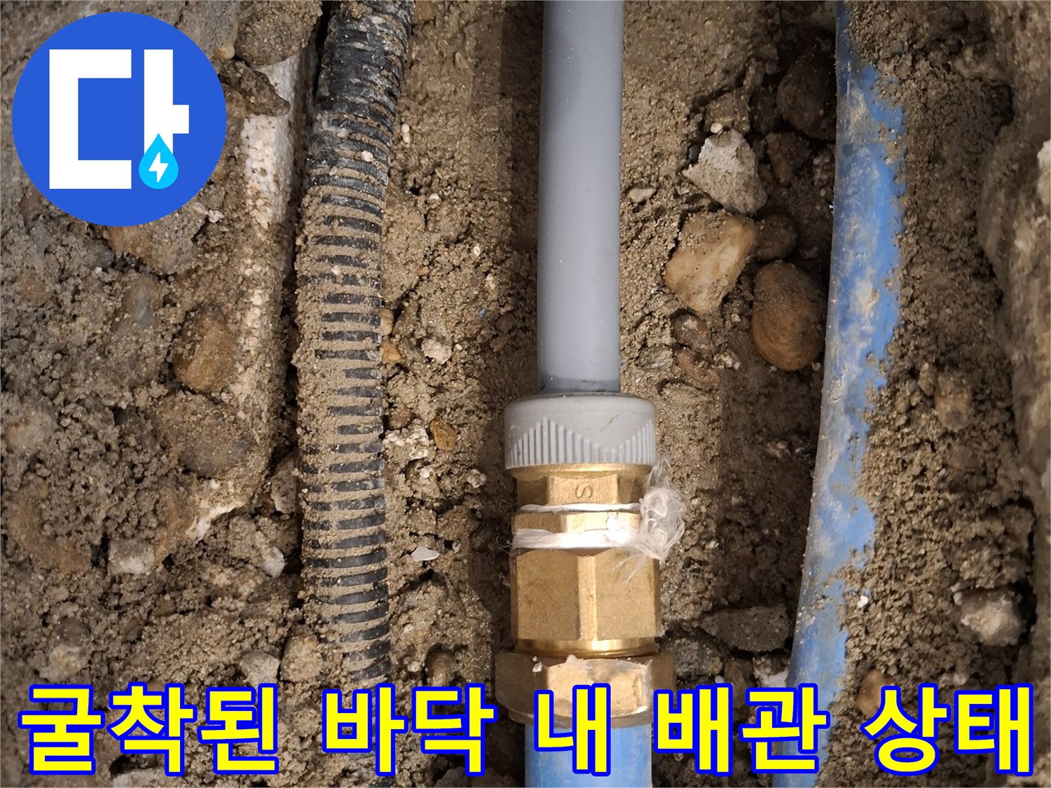 흙과 자갈 사이로 드러난 파손된 온수관 및 금속 부속 연결 부위