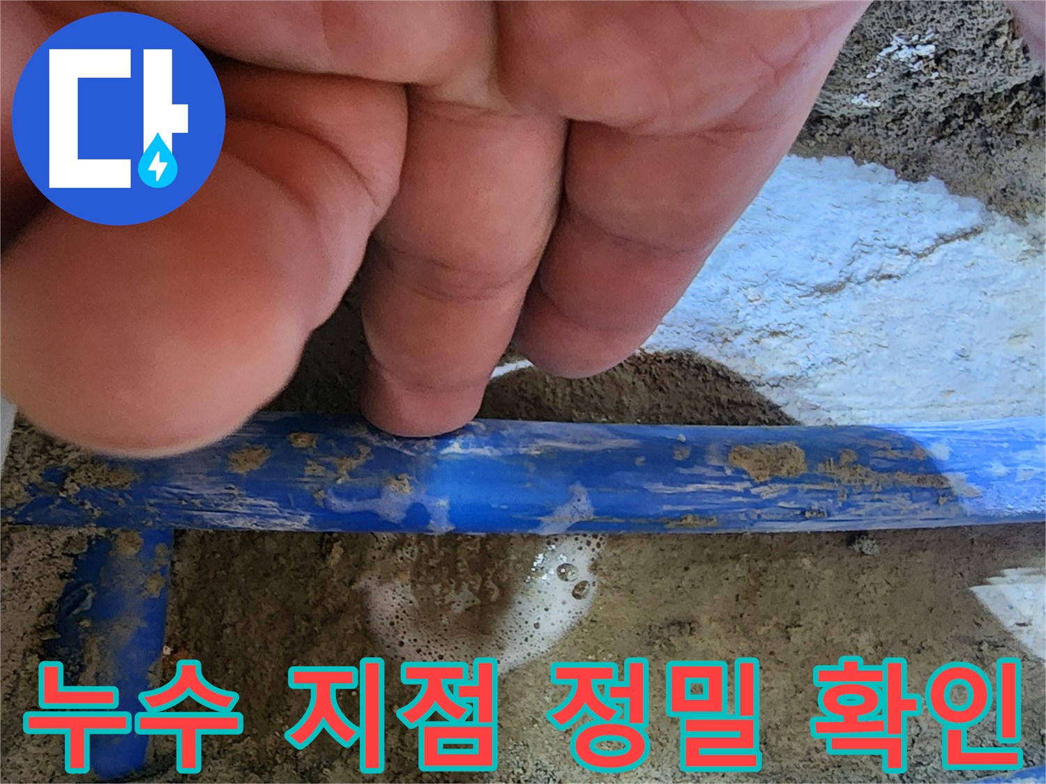 전문가의 손이-파란색 수도관의-누수 지점을 가리키며-거품으로 누수를-명확히 보여주는 사진