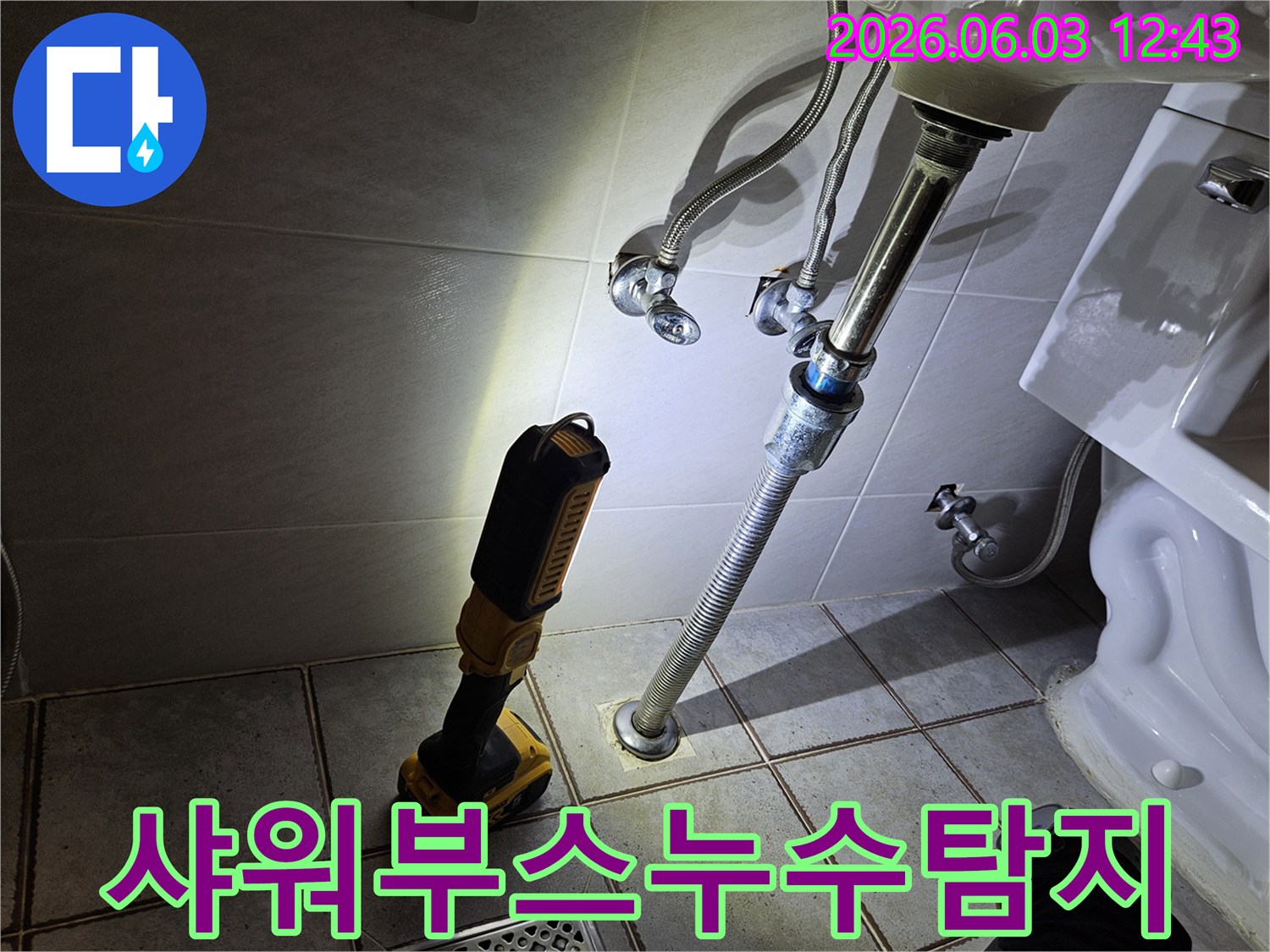 타일 바닥에 설치된 배관과-그 주변을 비추는-누수 탐지용 조명 장비가-정밀하게 작동하고 있습니다.