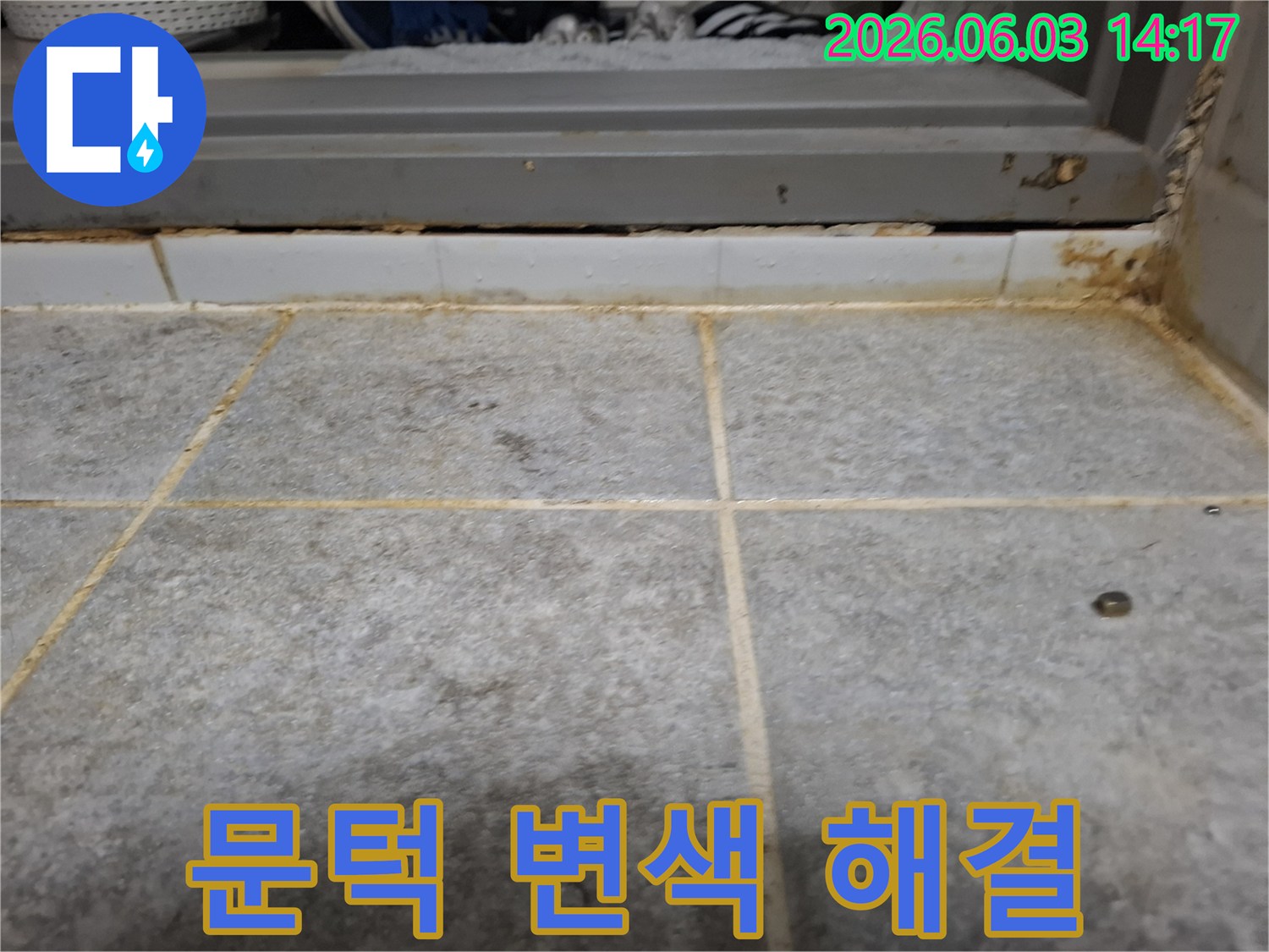 욕실 문턱 주변 타일과 줄눈에 누수로 인해 발생한-심한 변색과 오염 상태를 상세하게 보여주는 사진입니다.
