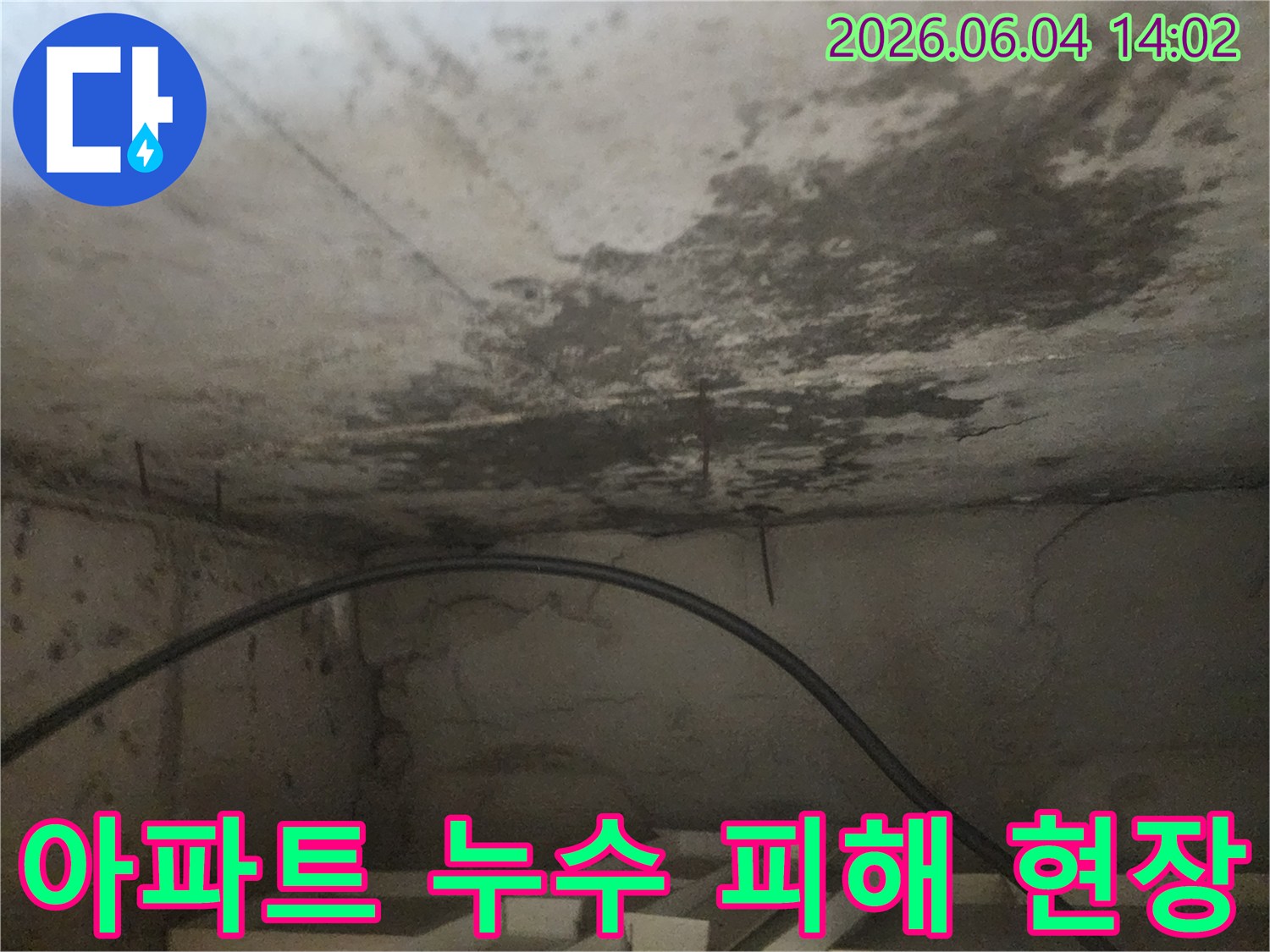 아파트 아래층 천장에 발생한-누수로 인한-심각한 물자국과-콘크리트 손상을 담은 사진입니다.