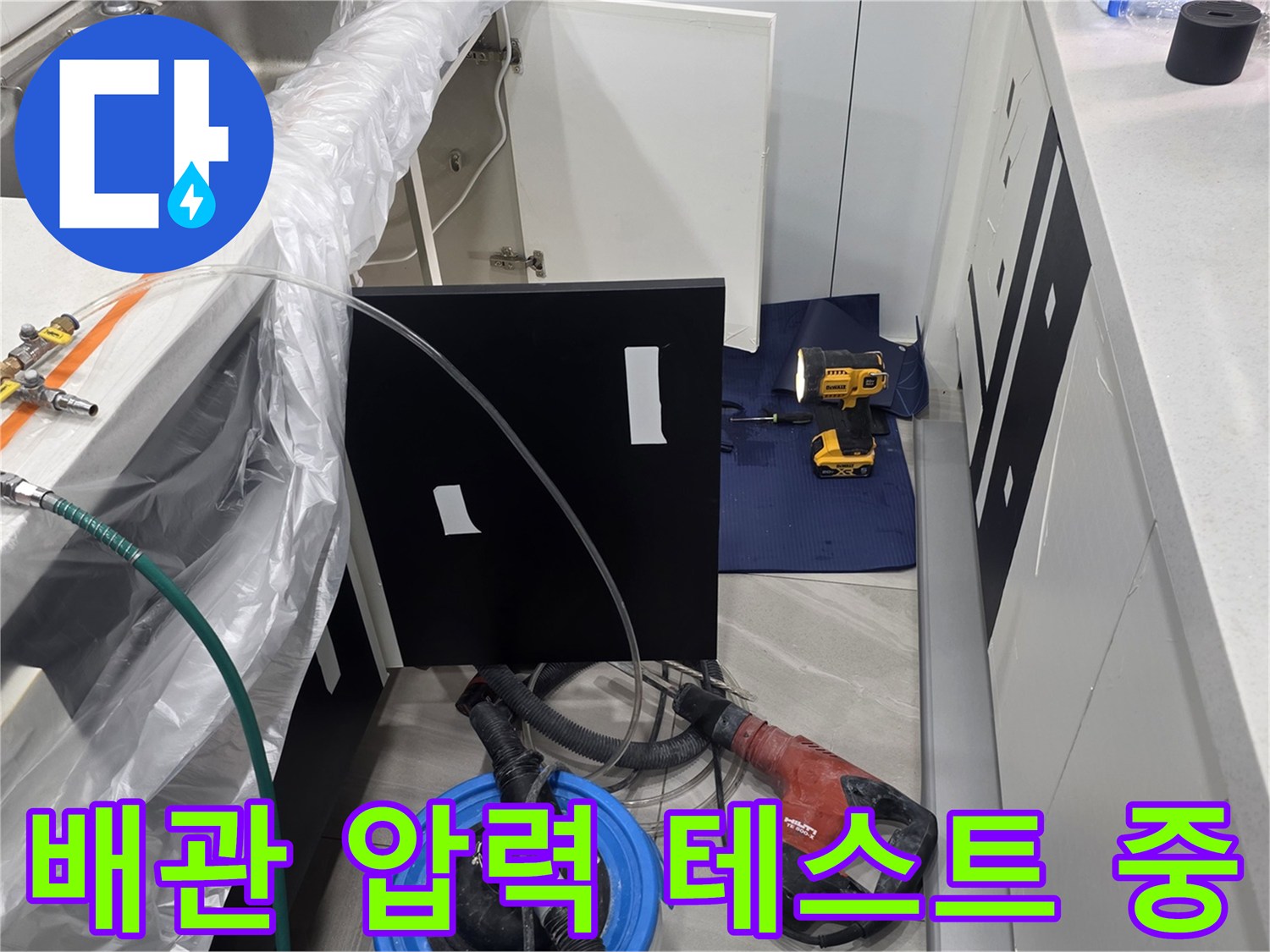 주방 싱크대 하부 배관에 압력계를 연결하여 공압 테스트를 진행하는 모습입니다.