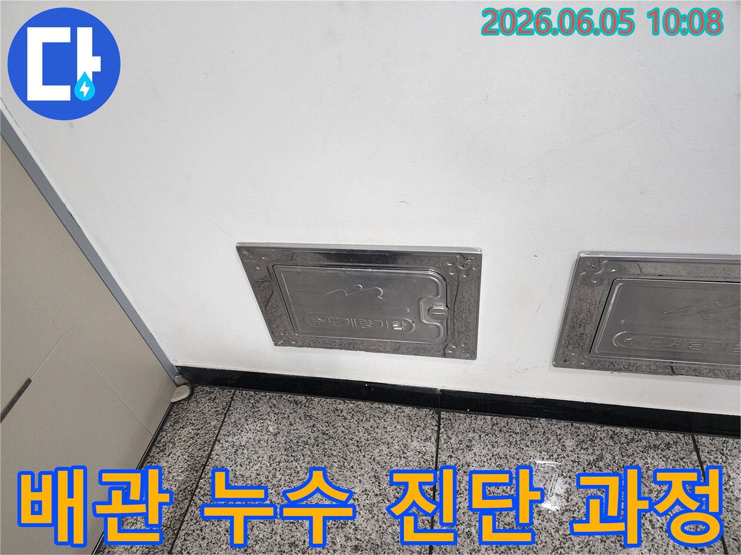 벽에 설치된-수도계량기함-덮개-주변에서-누수-원인을-찾는-작업-사진입니다.