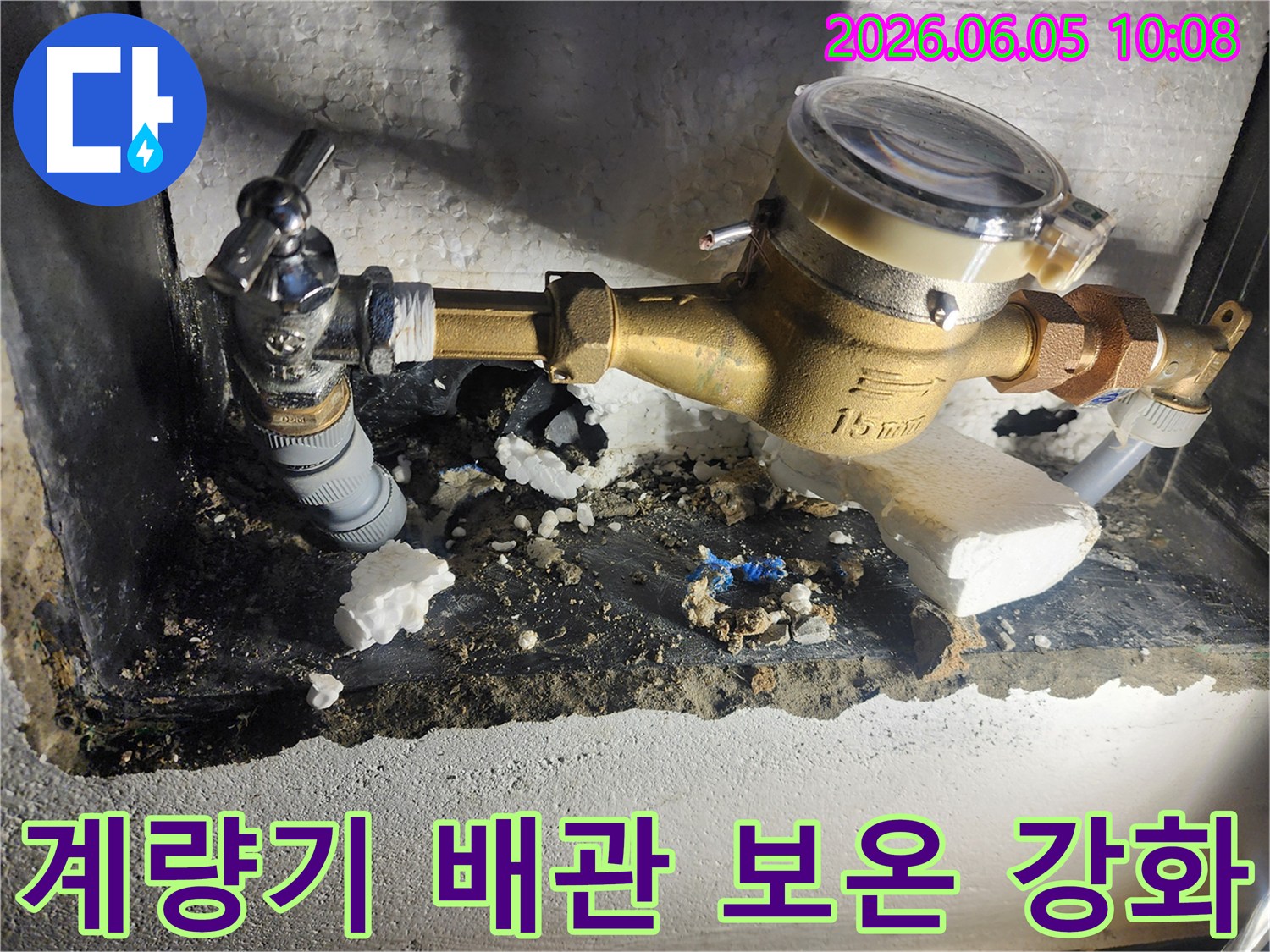 이 사진은 수도계량기 주변 누수 수리 후-새로운 단열재로 배관 보온을 강화하는 작업을 보여줍니다-겨울철 동파 방지-에너지 효율 증대