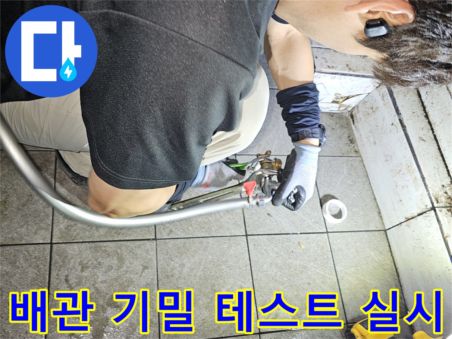 작업자가 배관 연결 부위에-압력 호스를 연결해 검사하는 장면