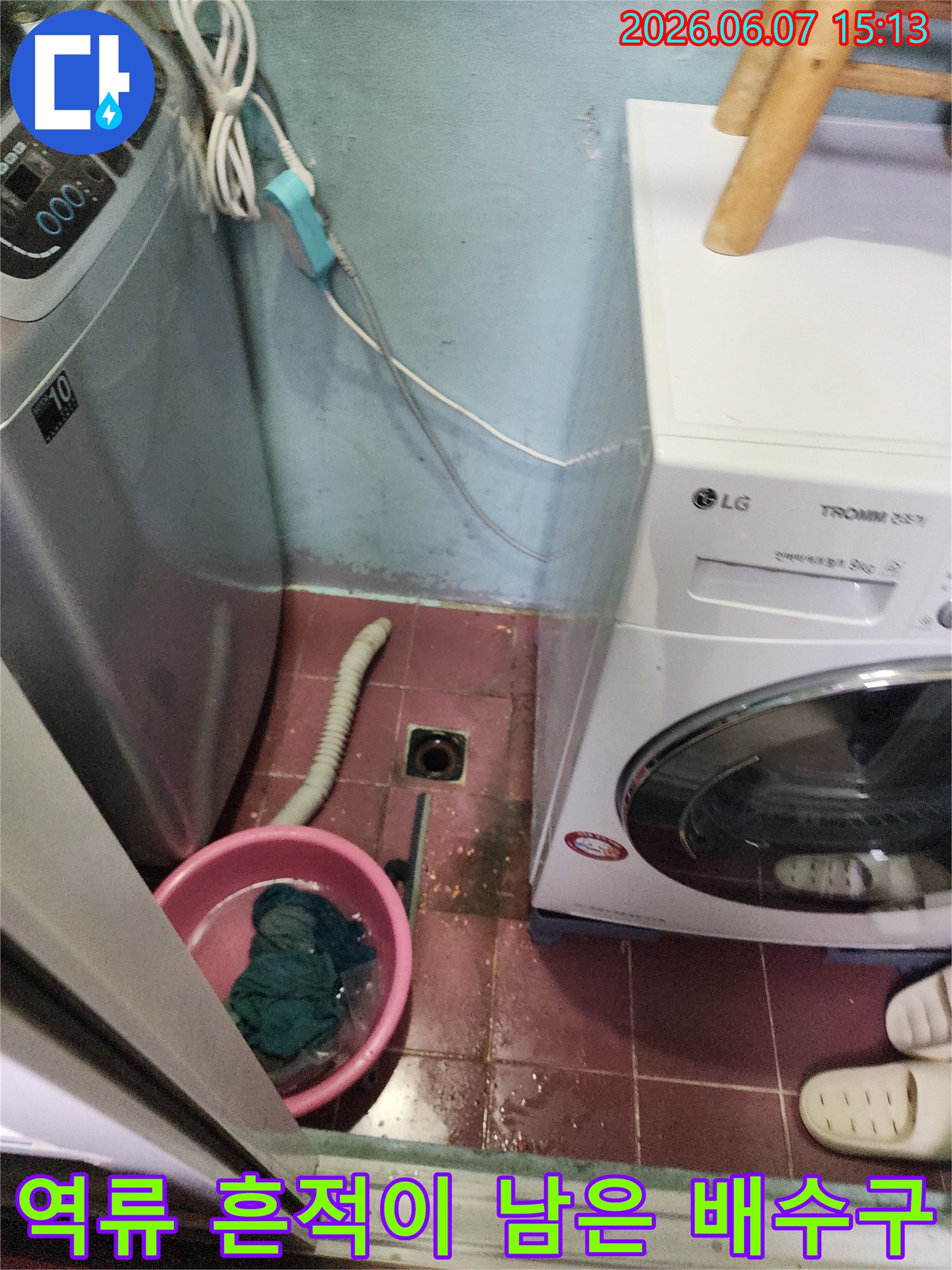 세탁기 아래쪽 배수구 주변에 물이 고여 있고 오염된 상태를 보여주는 사진입니다.