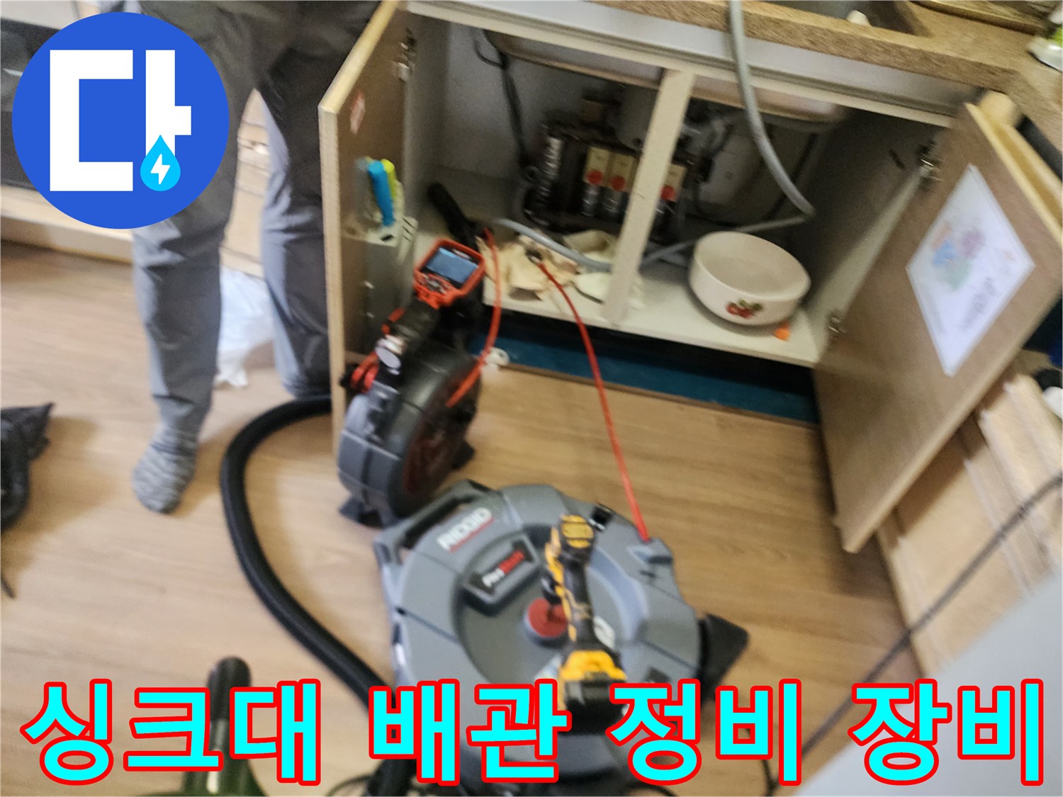 싱크대 하부장 내부의 막힌 배관을 청소하기 위한 전문 도구 배치