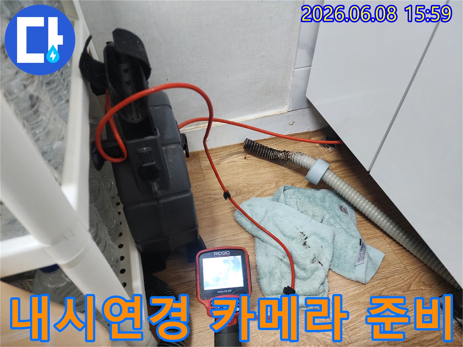 배관 내시경 장비와 연결된 빨간색 케이블이 싱크대 하부 배관 근처에 놓여 있습니다.