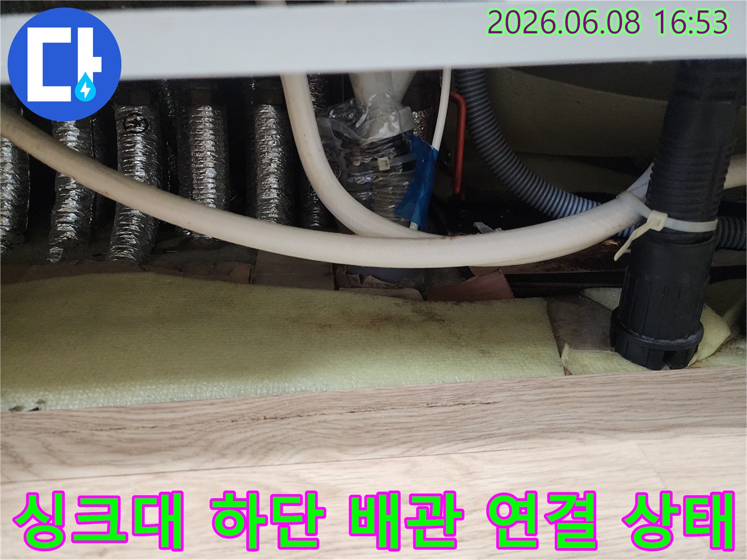 랩과 타이로 임시 조치된 싱크대 배관의 연결 부위 근접 촬영입니다.