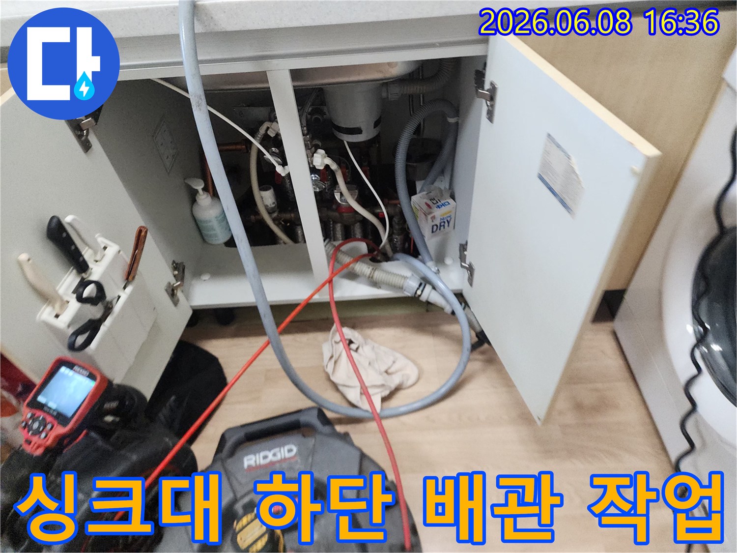 싱크대 아래쪽 배관 구조와 작업 중인 전문 장비의 모습입니다.