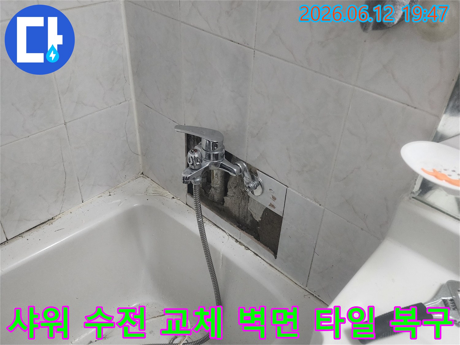 욕실 벽면의 타일이 제거된-상태에서-새로운 샤워 수전이-설치되고-벽면 타일 복구 작업이-진행되는-모습을-담은-사진입니다.
