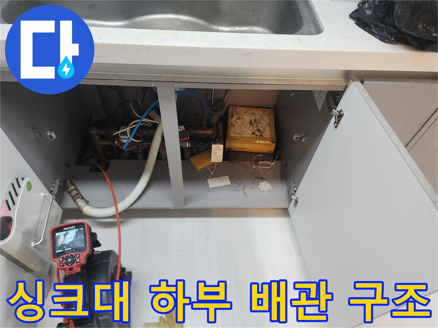 싱크대 아래쪽 꺾인 호스와 연결된 배수관의 상태를 근접 촬영한 사진