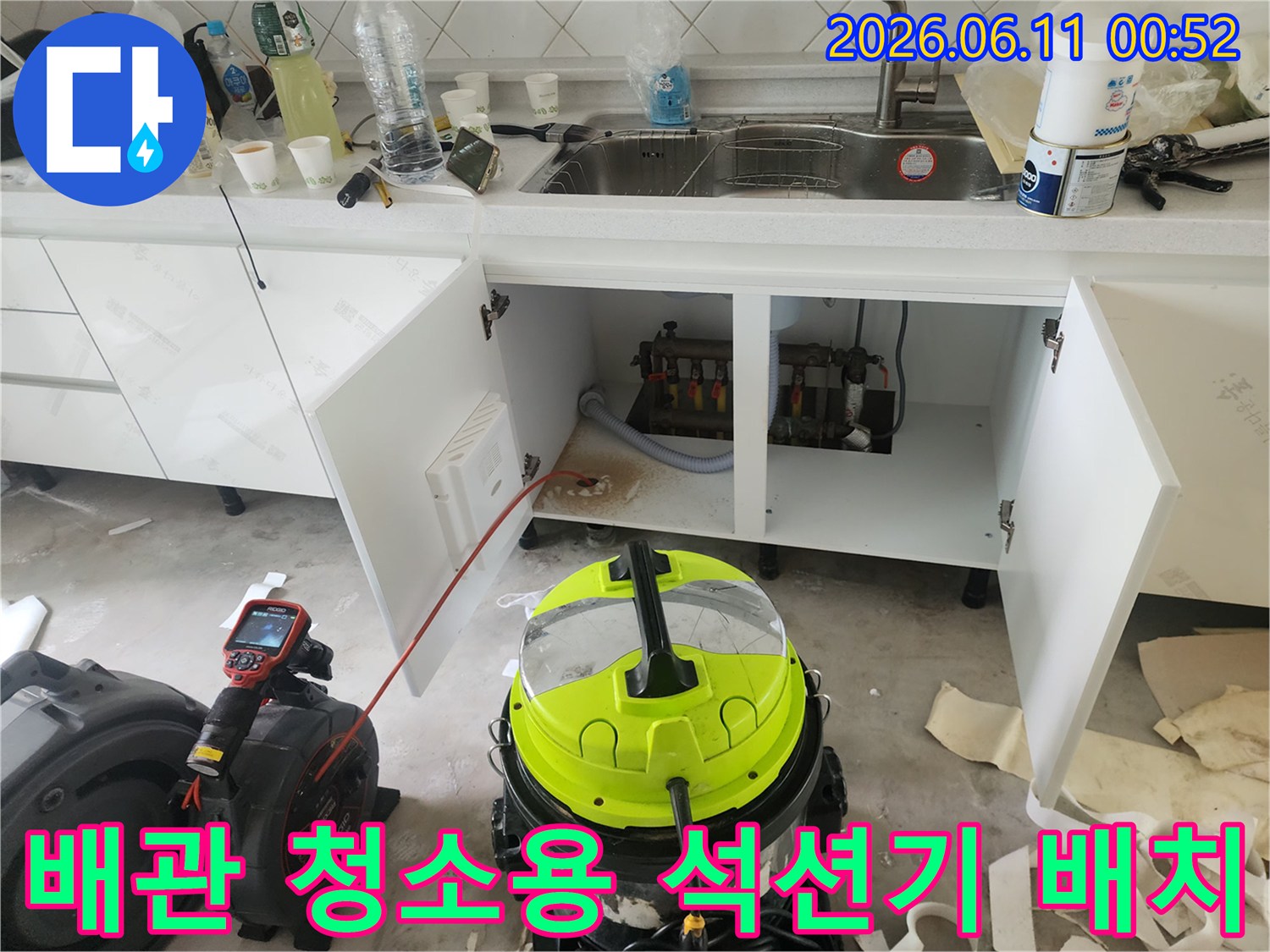 싱크대 하부 배관 옆에 놓여 있는 노란색 전문 석션 장비와 작업 도구입니다.