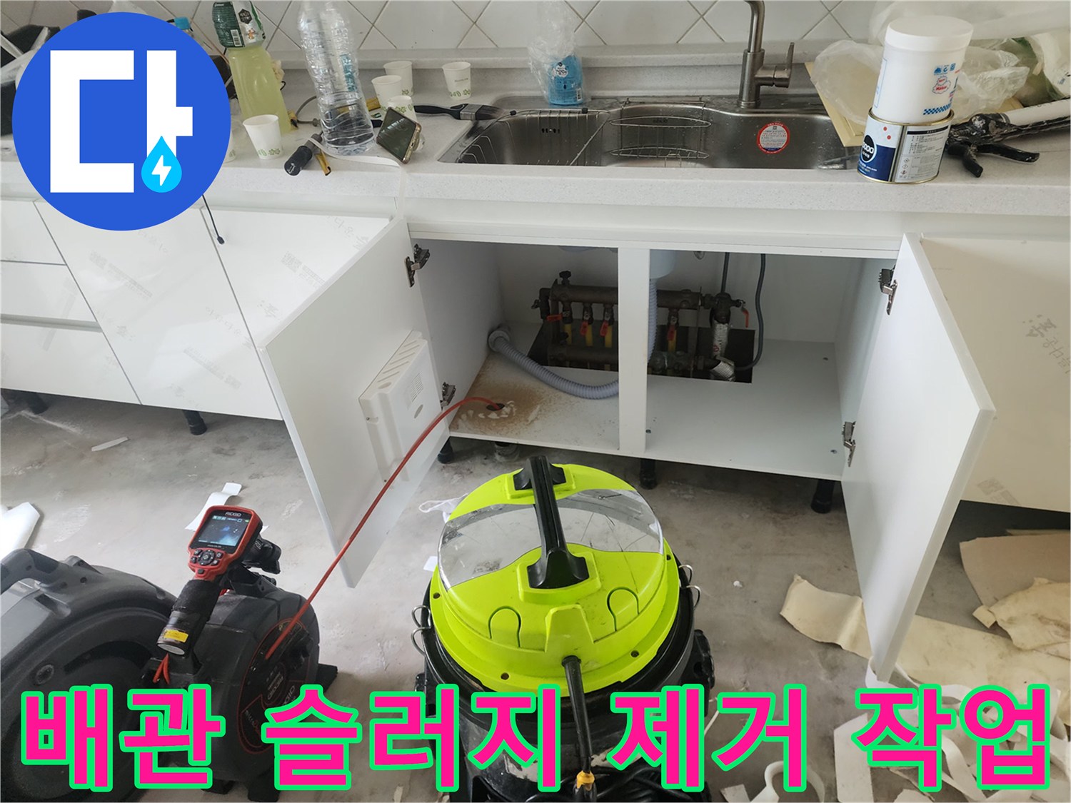 주방 싱크대 밑 배관 청소를 위해 준비된 석션 장비와 배관 모습