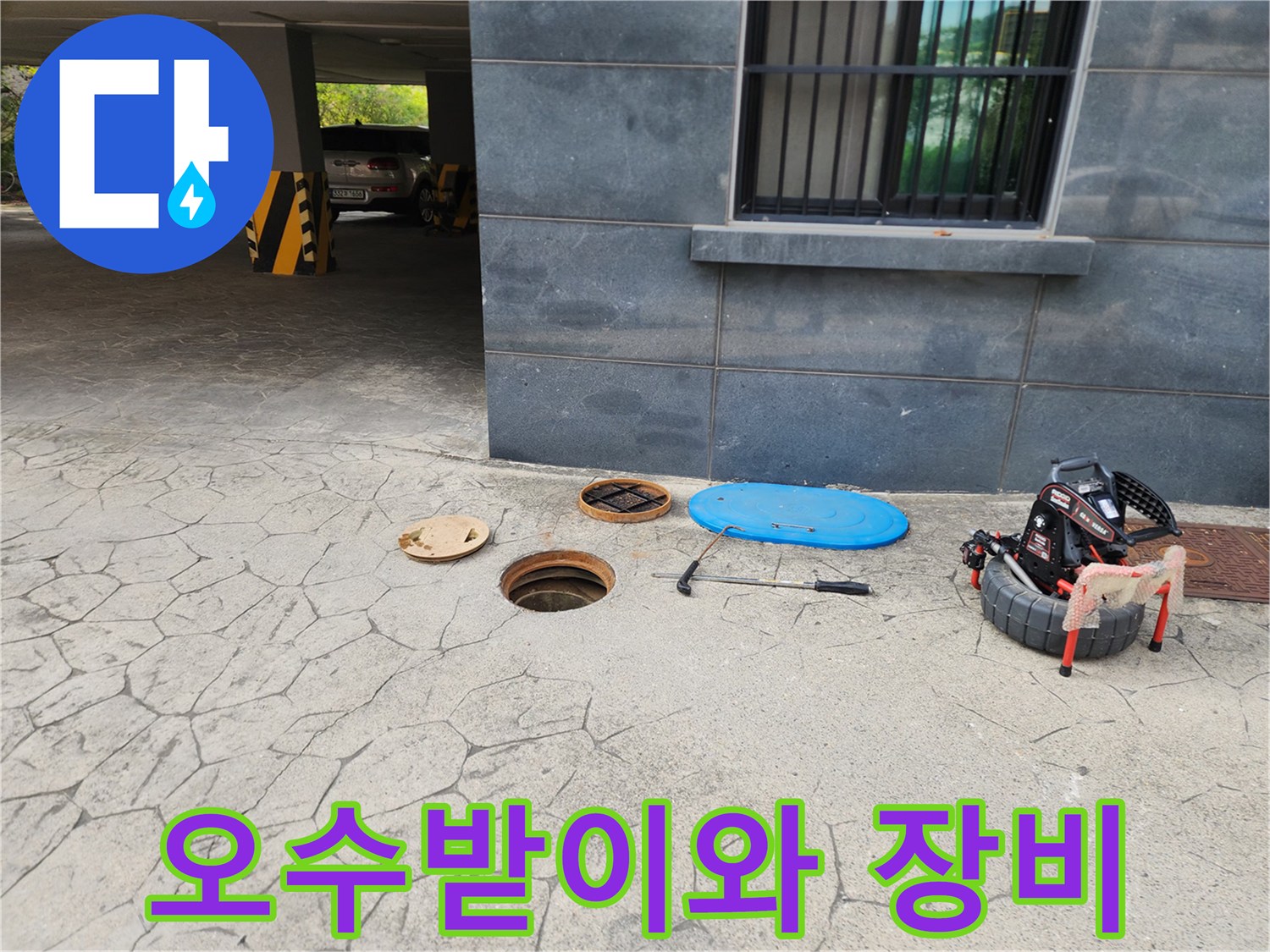 건물 외부 오수받이 주변에 놓인 고압세척 장비와 점검 도구