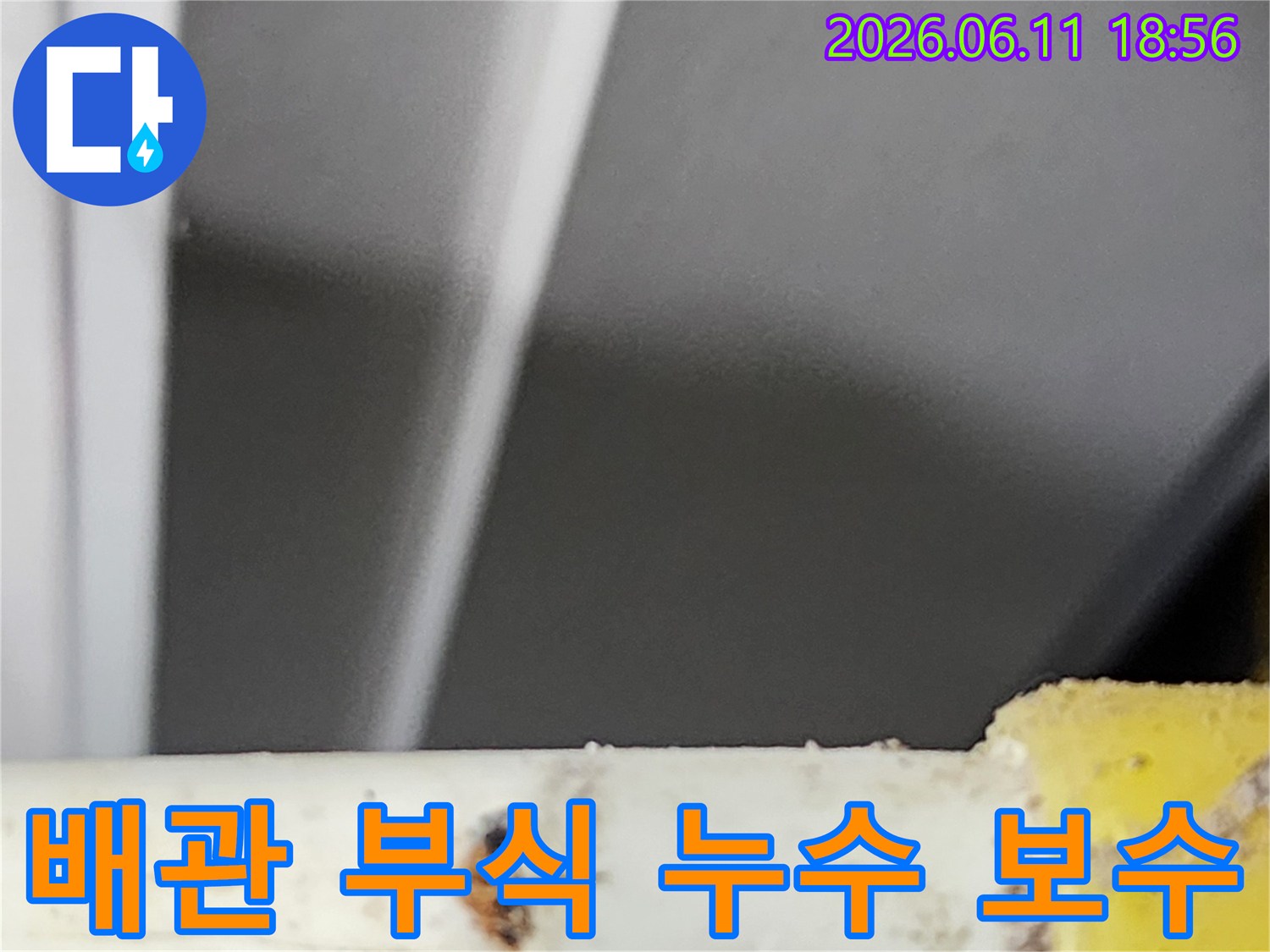 부식된 배관에서 발생한 누수 지점을-전문가가 확인하고-보수 작업을 준비하는 현장 사진입니다.