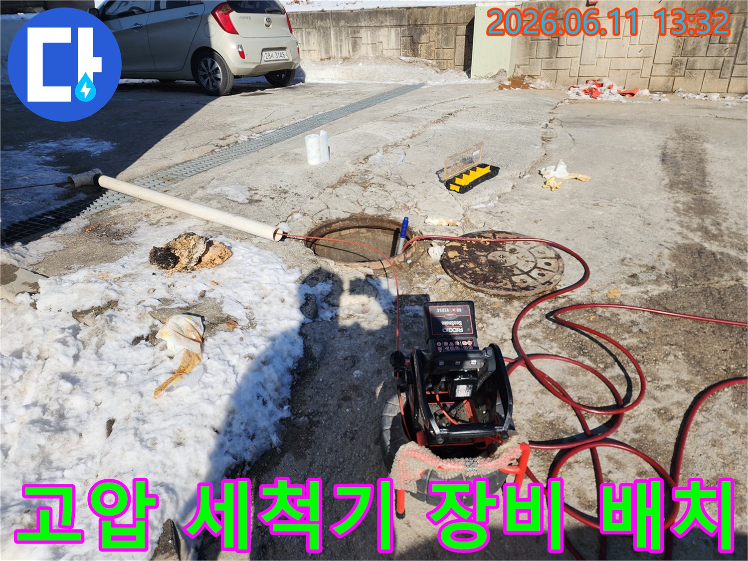 맨홀 뚜껑 근처에 설치된-전문가용 고압 세척기와 배관 연결 호스