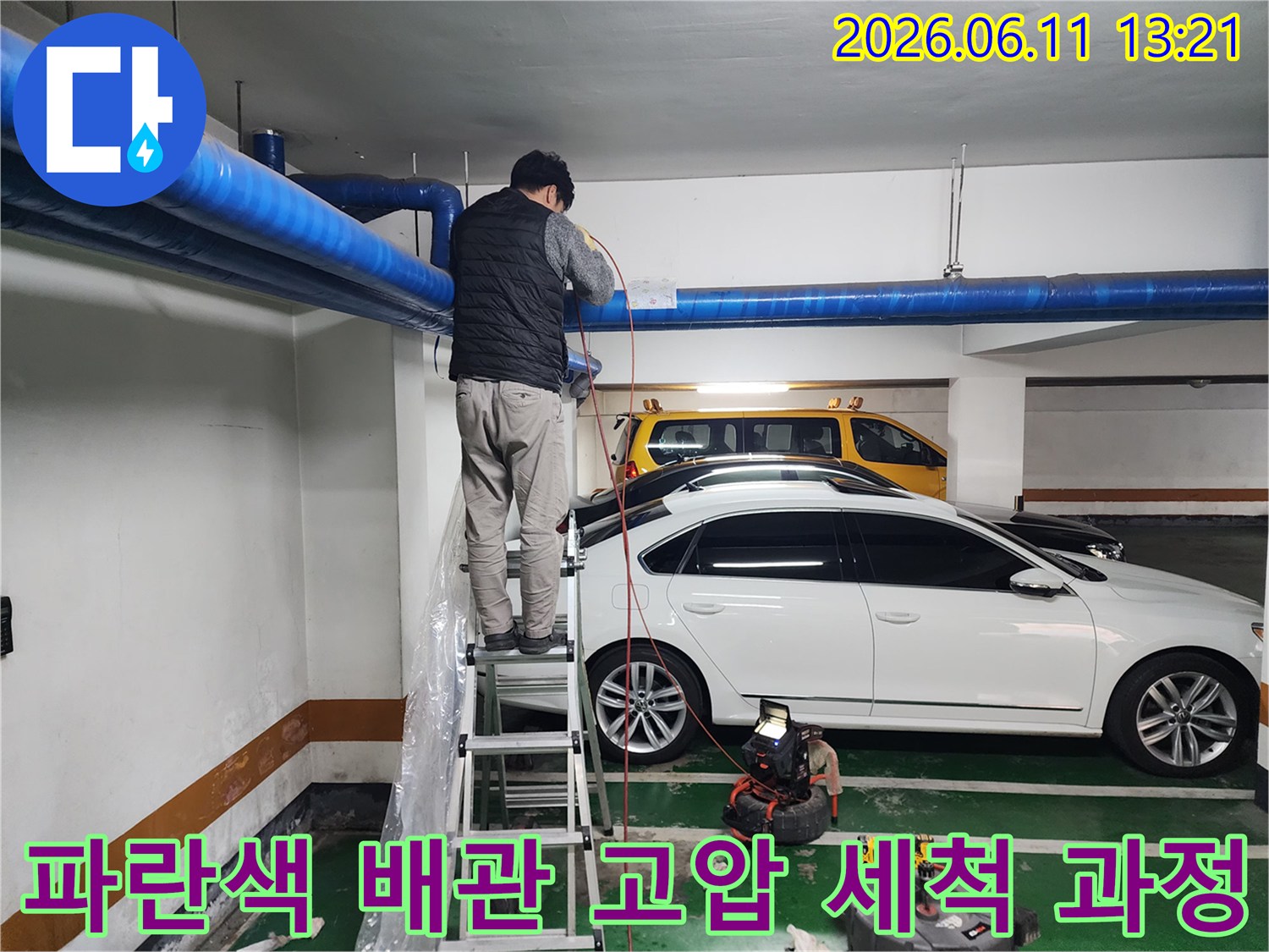 지하주차장 천장의 파란색 대형 배관을 향해 작업 중인 모습