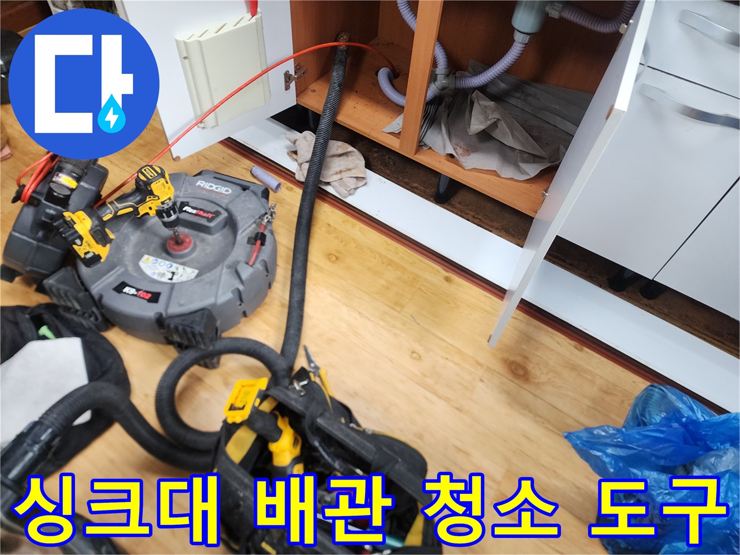 싱크대 하부 배수관의 막힌 부분을 뚫기 위해 준비된 전문 전동 장비 세트