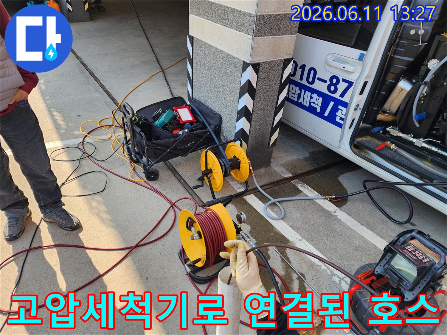 고압 세척 작업을 위해 차량에서 연결된 노란색 호스 릴과 배관 장비들입니다.