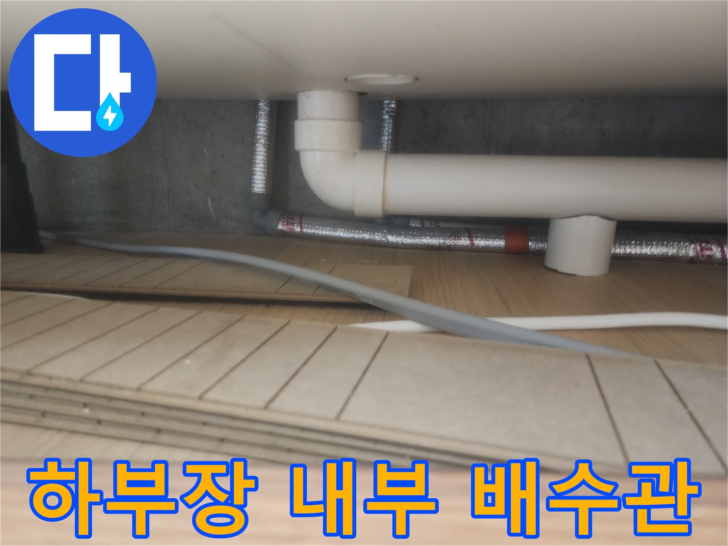 싱크대 하부장 아래쪽을 비춘 흰색 PVC 배수관과 연결 부위 사진
