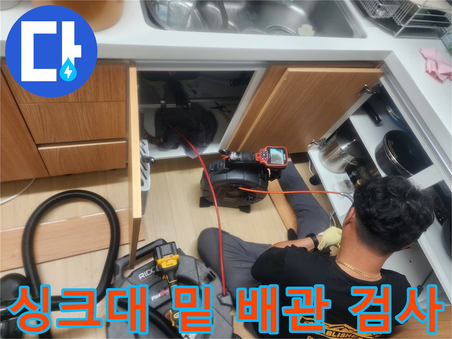 싱크대 아래쪽 공간에서 내시경 장비를 이용해 배관을 점검하는 엔지니어