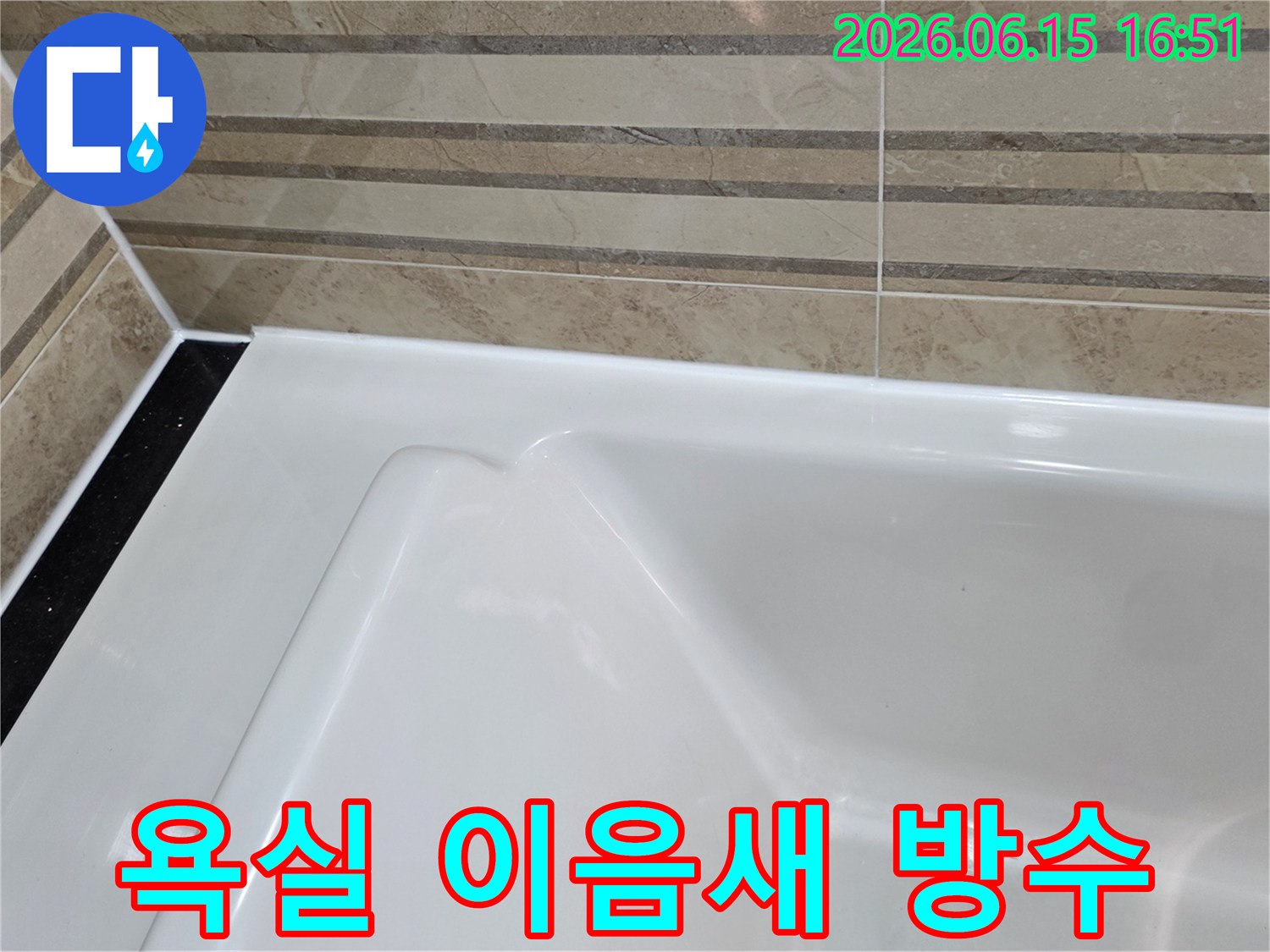 이 이미지는 욕실의 타일 벽면과-욕조가 만나는 접합부에-새롭게 적용된-고품질 방수 마감재를 보여주며-이는 물의 침투를 효과적으로 막아-누수를 예방합니다.