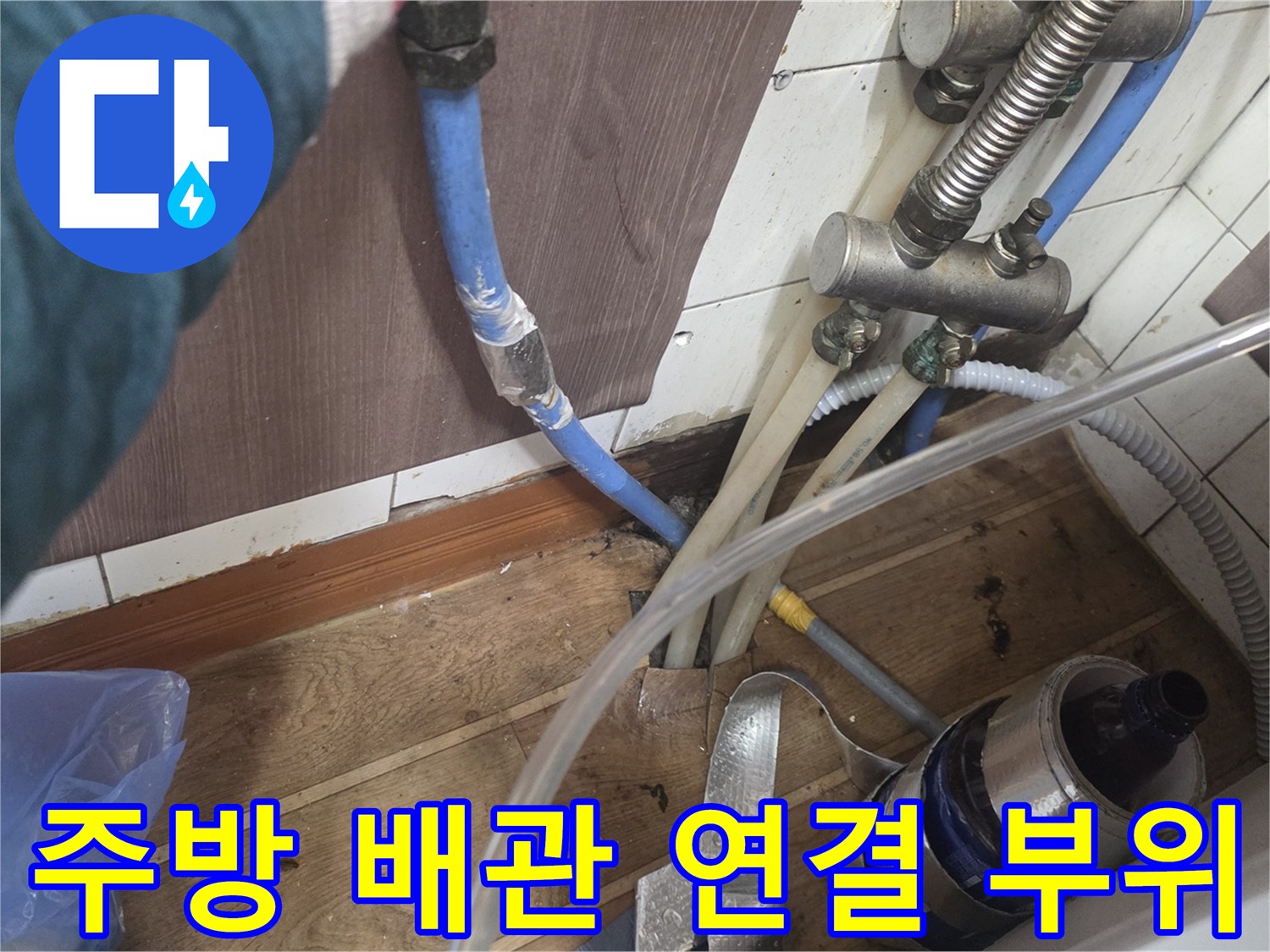 파란색 온수 호스와 금속 밸브가 맞물려 있는 수도 설비의 상세 모습입니다.