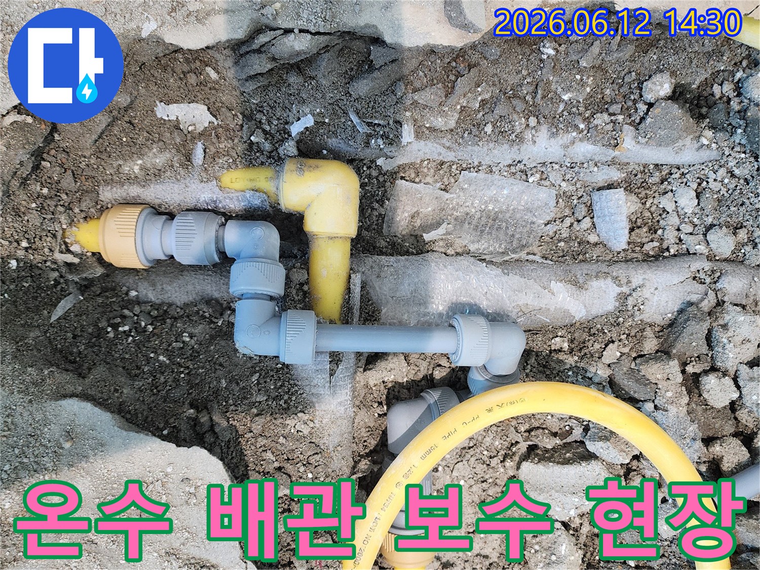 땅을 파헤쳐 드러난 노란색 가스-배관과 회색 온수-배관이 연결된 누수-탐지 및 보수 공사 현장의 모습입니다