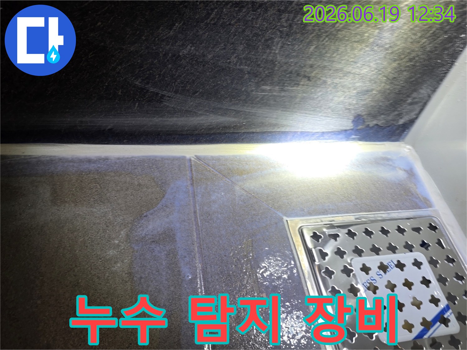욕실-바닥-타일과-배수구-주변에-물이-고여있는-누수-현장에서-최첨단-탐지-장비를-활용하는-사진입니다