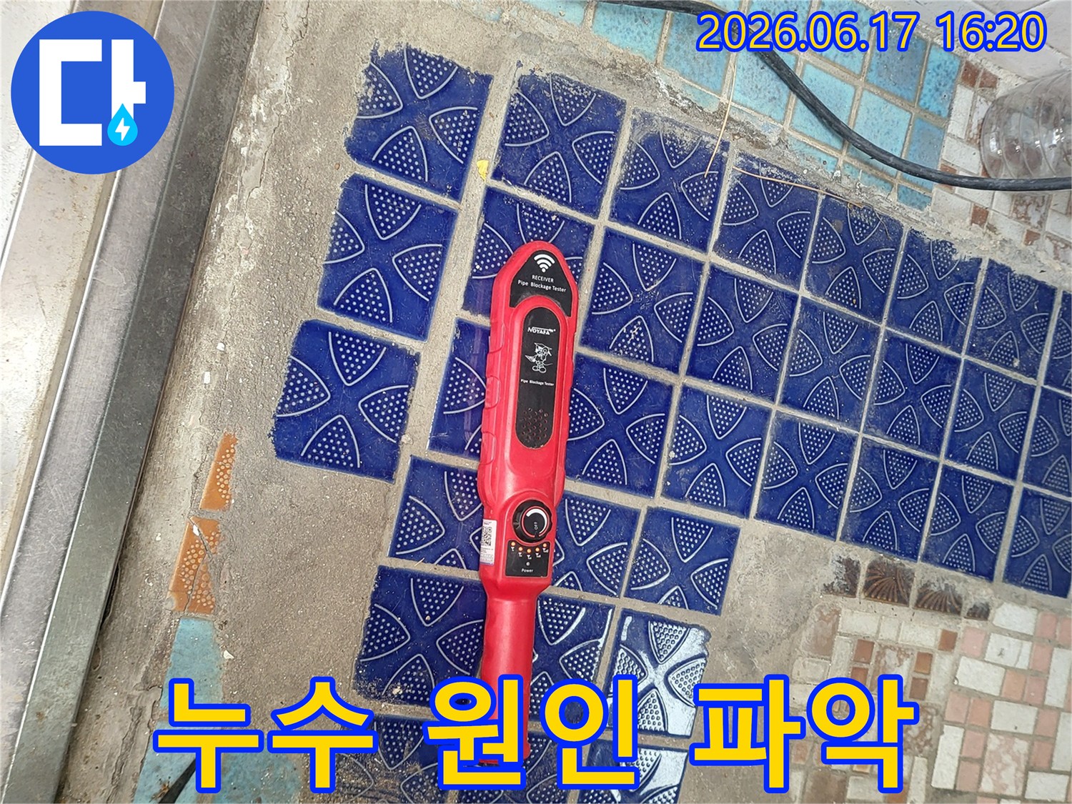 파란색 타일이 부분적으로 제거된 욕실 바닥에-붉은색 누수탐지 장비가 놓여-누수 원인을 정확히 파악하는 중인 모습
