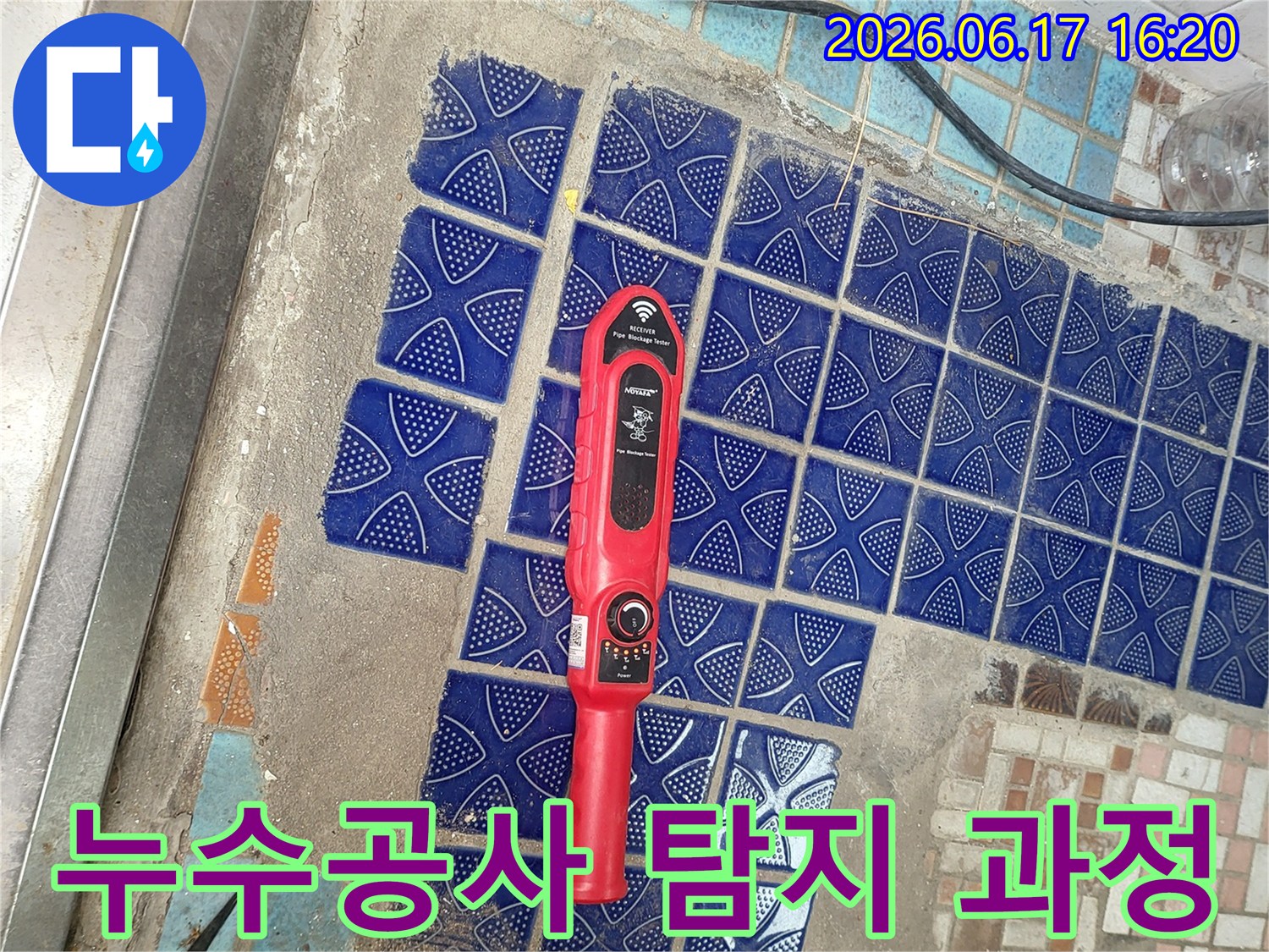 파란색 타일이 부분적으로 제거된 욕실 바닥에-붉은색 누수탐지 장비가 놓여-누수공사 전 정밀 탐지 중인 모습
