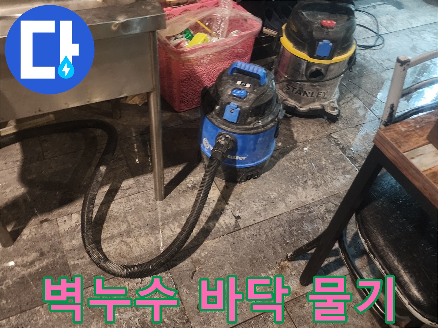 벽 누수로 인해-바닥에 고인 물을-신속하게 흡입하고-습기를 제거하기 위해-사용되는-산업용 석션 장비 두 대가-바닥에 놓여있는 모습입니다.