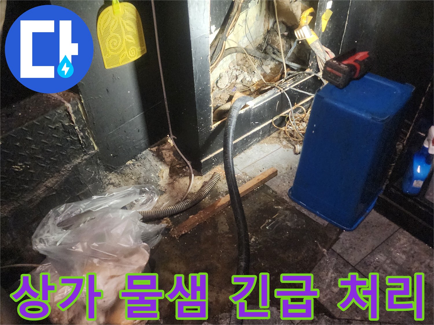 어두운 상가 바닥 아래에서 복잡하게 얽힌 배관과 전선-그리고 물이 새는 흔적을 보여주며 긴급 누수 처리를 진행하는 현장 이미지