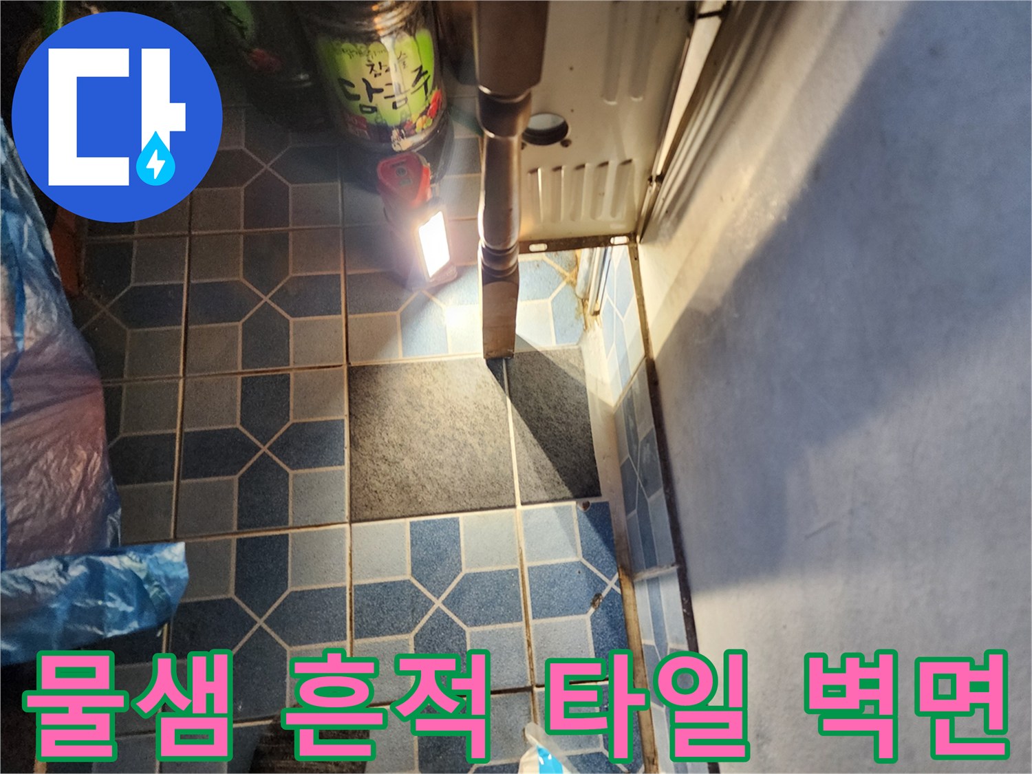 조명을 비추어 확인 중인 보일러실 타일 벽