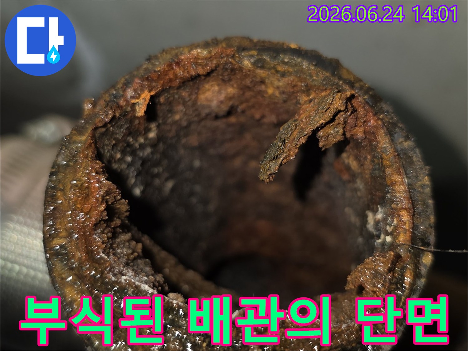 녹슬고 이물질로 가득 찬-노후 배관의 단면을 촬영한 사진입니다.