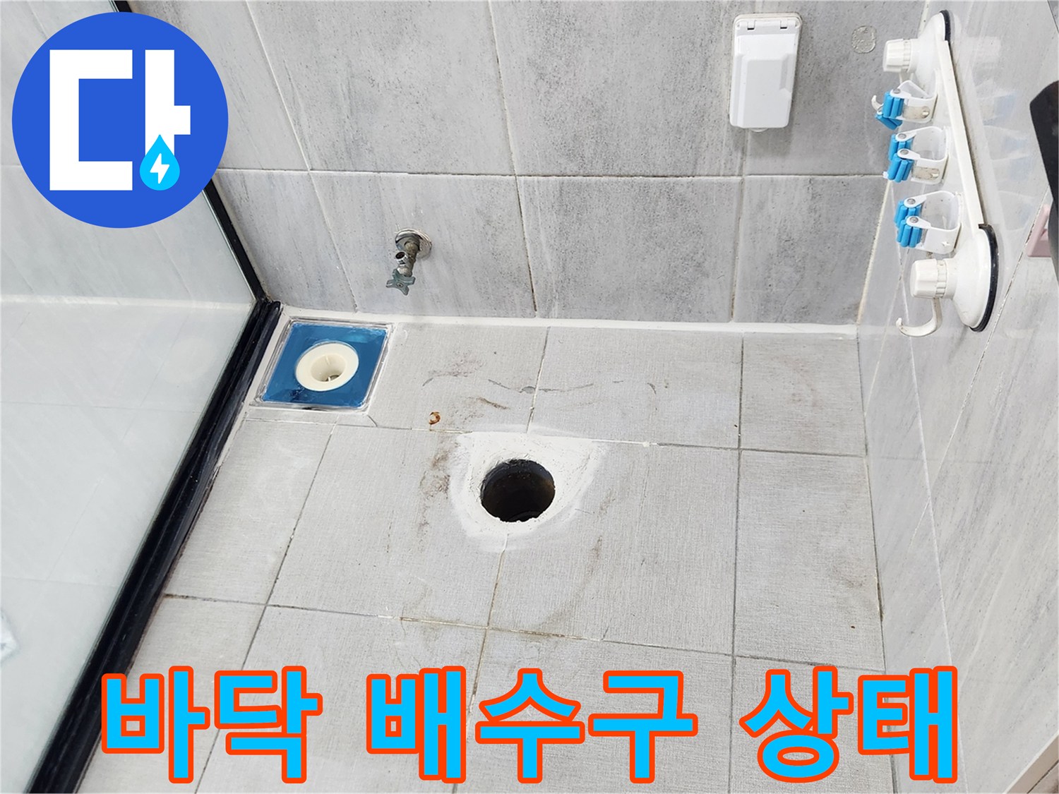 화장실 바닥에 위치한 배수구 유가와 타일 면을 촬영한 사진입니다.