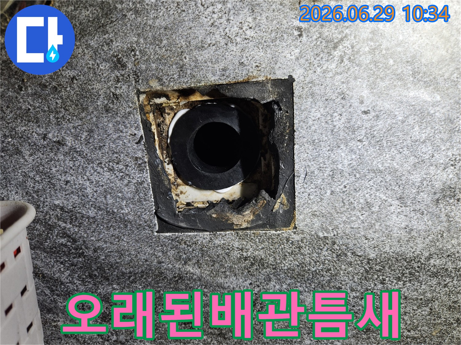 이 사진은 노후된 아파트 배관 틈새에서 발견된 누수 흔적을 보여주며-긴급한 보수 작업이 필요함을 시사합니다.