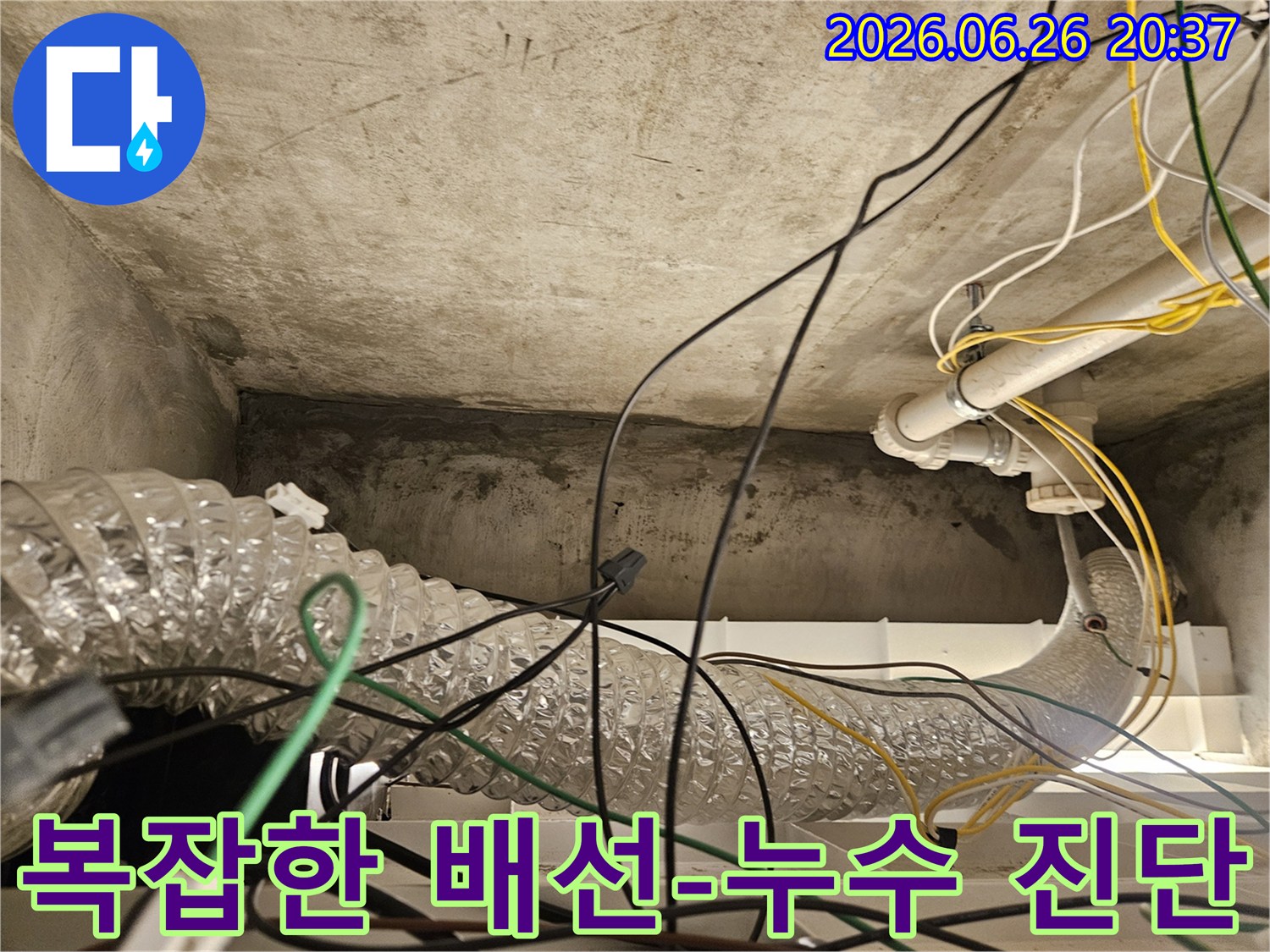 이 사진은 천장 내부의 얽히고설킨 전기 배선과-환기 덕트-그리고 배관 주변의-누수 흔적을 상세히 보여줍니다.