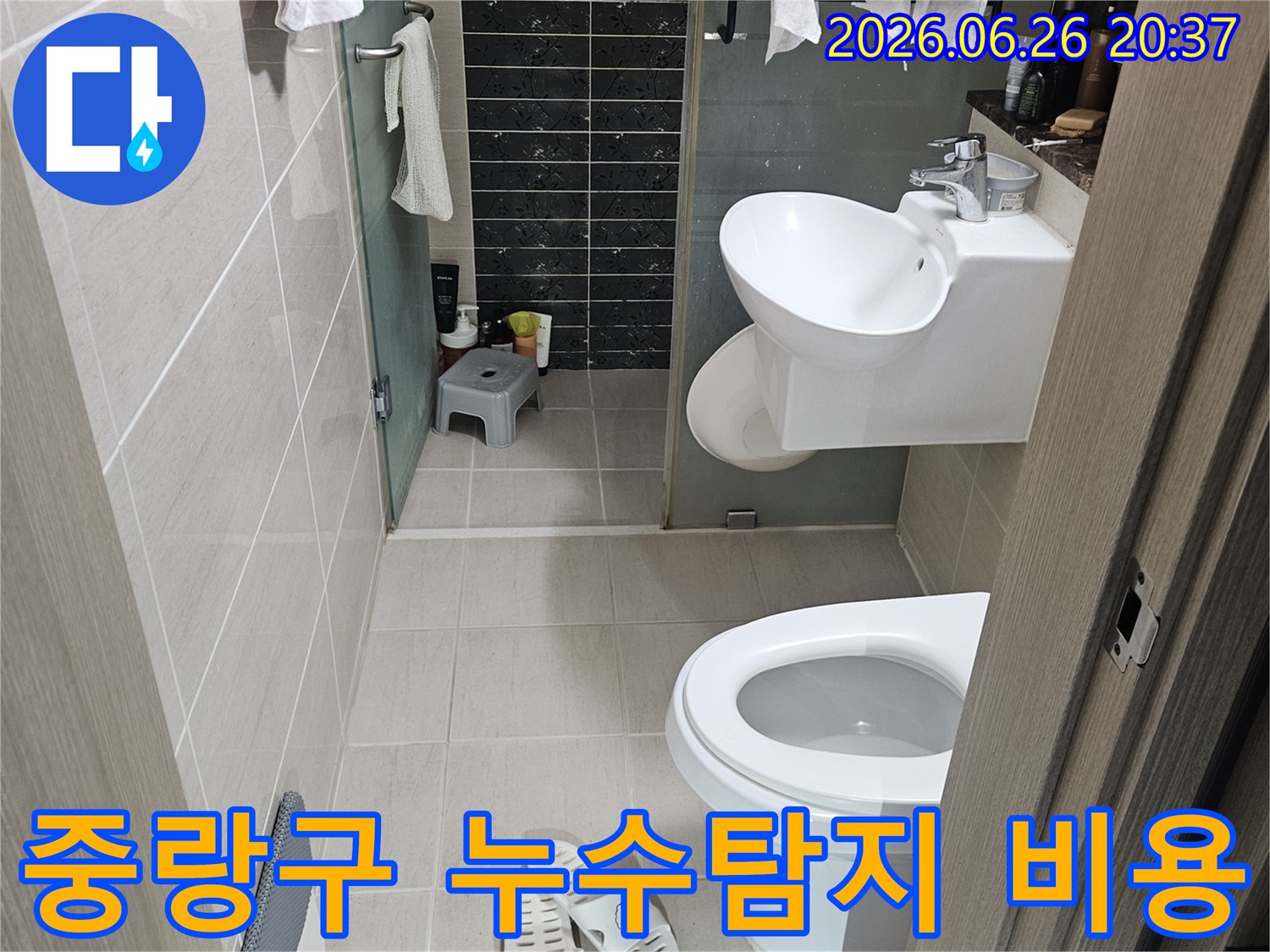 이 이미지는-서울 중랑구의 한 화장실에서-누수 탐지 비용 산정을 위해-현장 점검 중인 모습을 담고 있습니다-변기와 세면대가 보입니다
